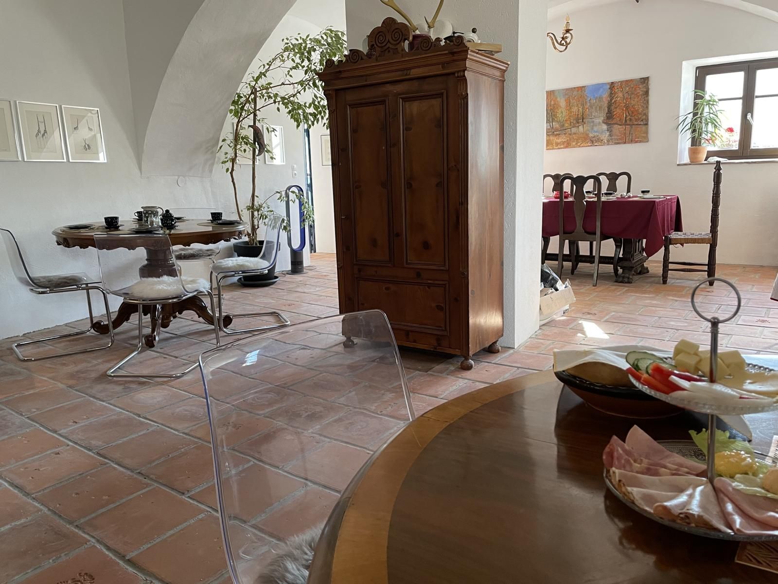 Innenansicht eines gemütlichen Raumes mit Holzmöbeln, Esstisch und Dekorationen.