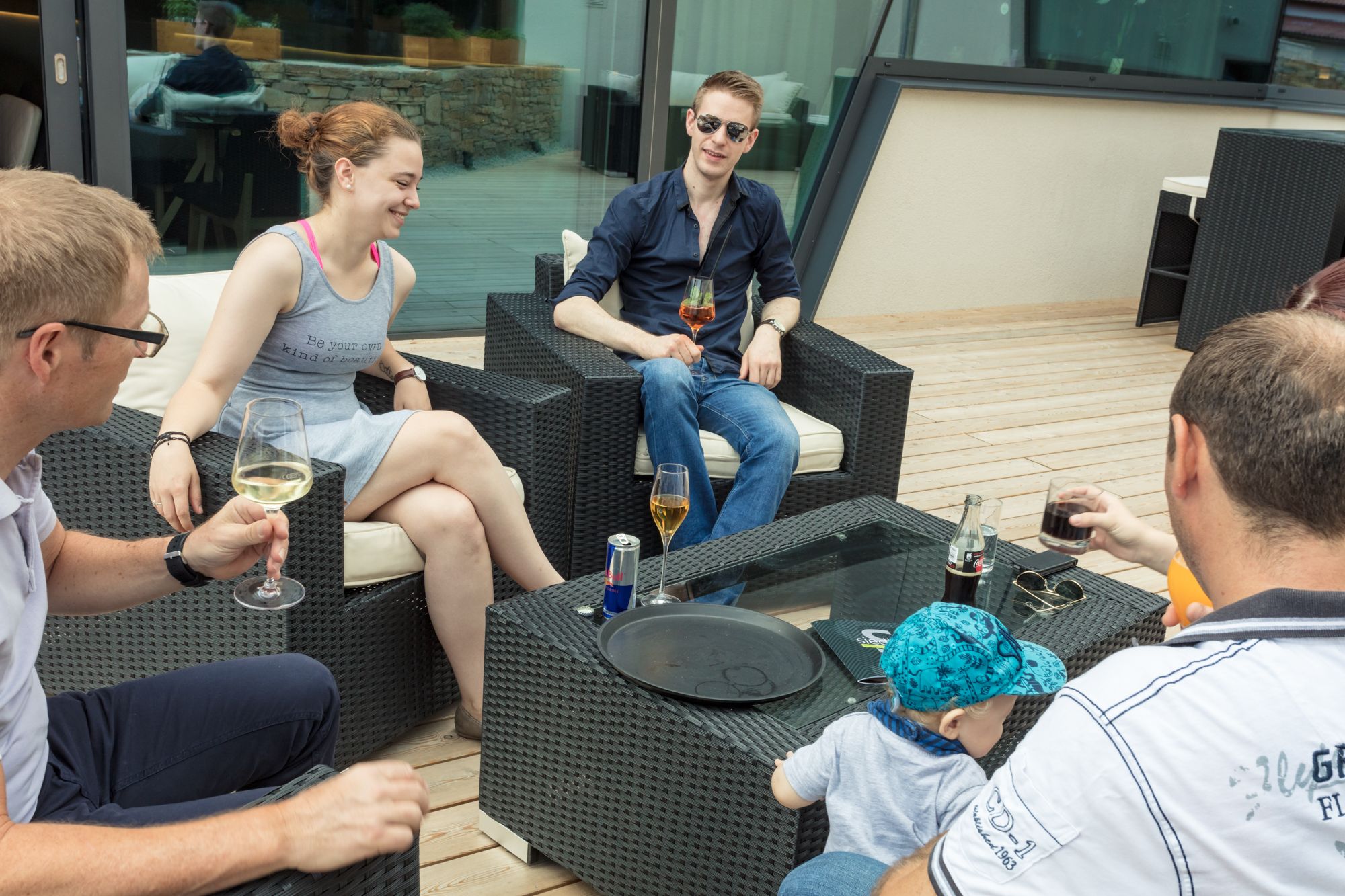 Gruppe von Menschen sitzt auf einer Terrasse und trinkt Getränke.