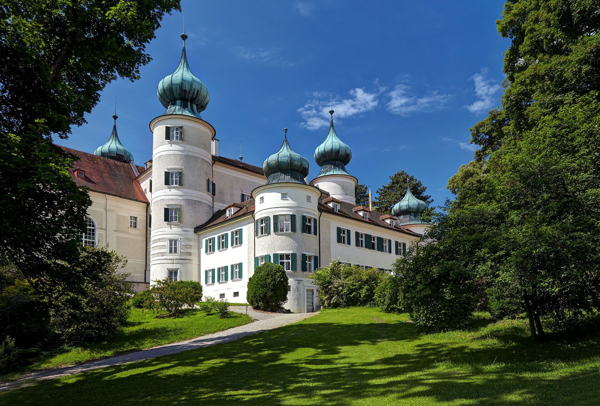 Umgeben von üppigem Grün und majestätischen Bäumen strahlt das Schloss Artstetten im Sommer eine einladende Atmosphäre aus. Die beeindruckende Architektur mit ihren markanten Türmen und dem strahlend blauen Himmel im Hintergrund schafft eine malerische Kulisse, die zum Verweilen einlädt. Hier erleben Besucher die harmonische Verbindung von Geschichte und Natur.