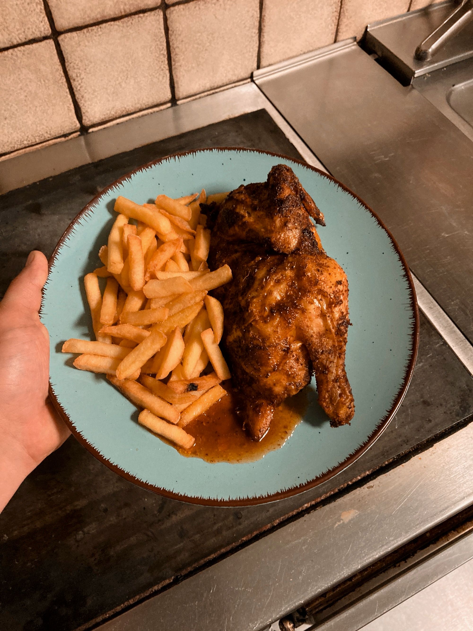 Fertig zubereitetes Grillhuhn mit Pommes.