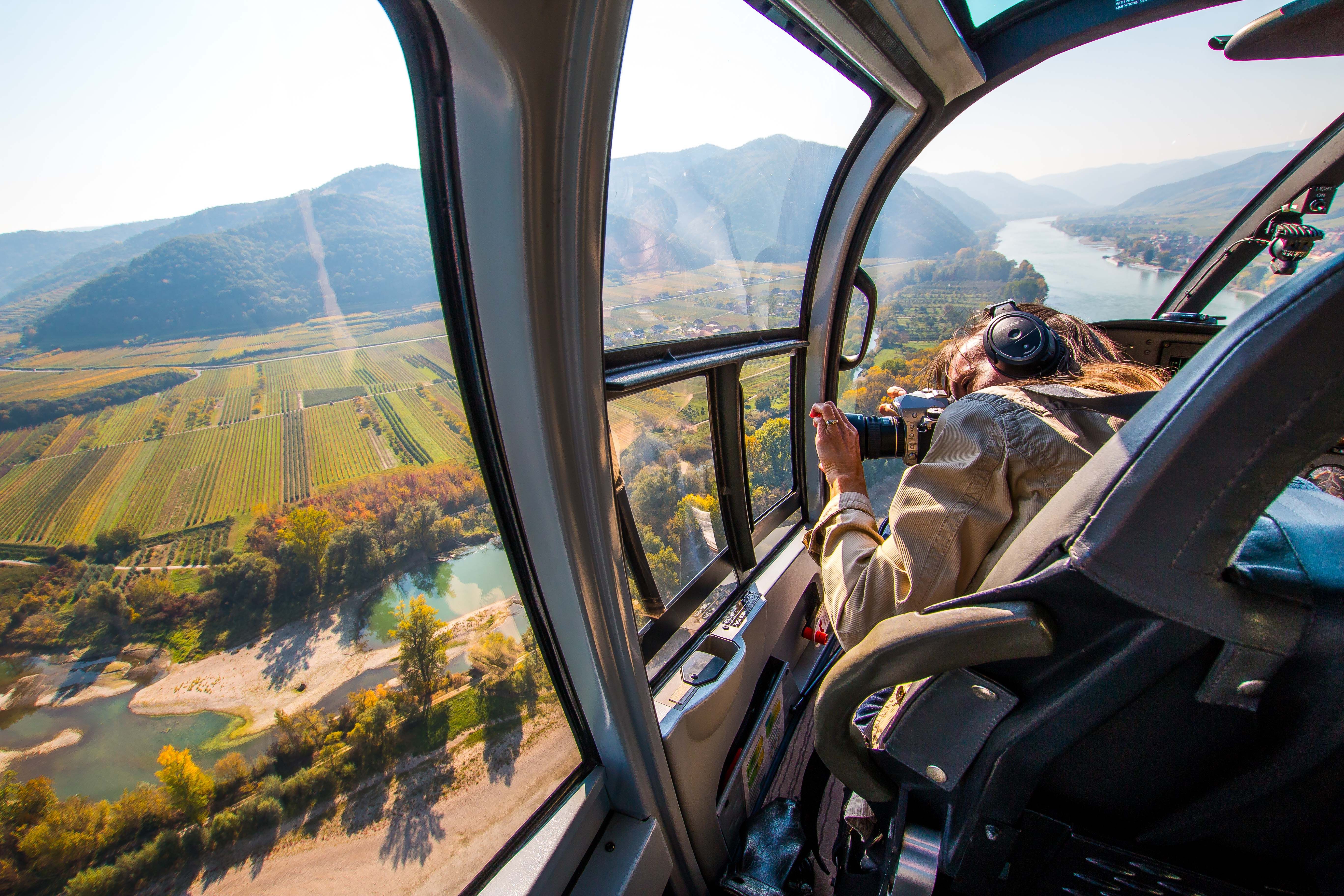 Blick aus einem Helikopter auf eine Landschaft mit Fluss und Feldern.