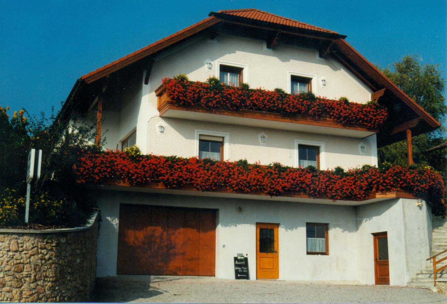 A two-storey guest house with red flowers on the balconies.