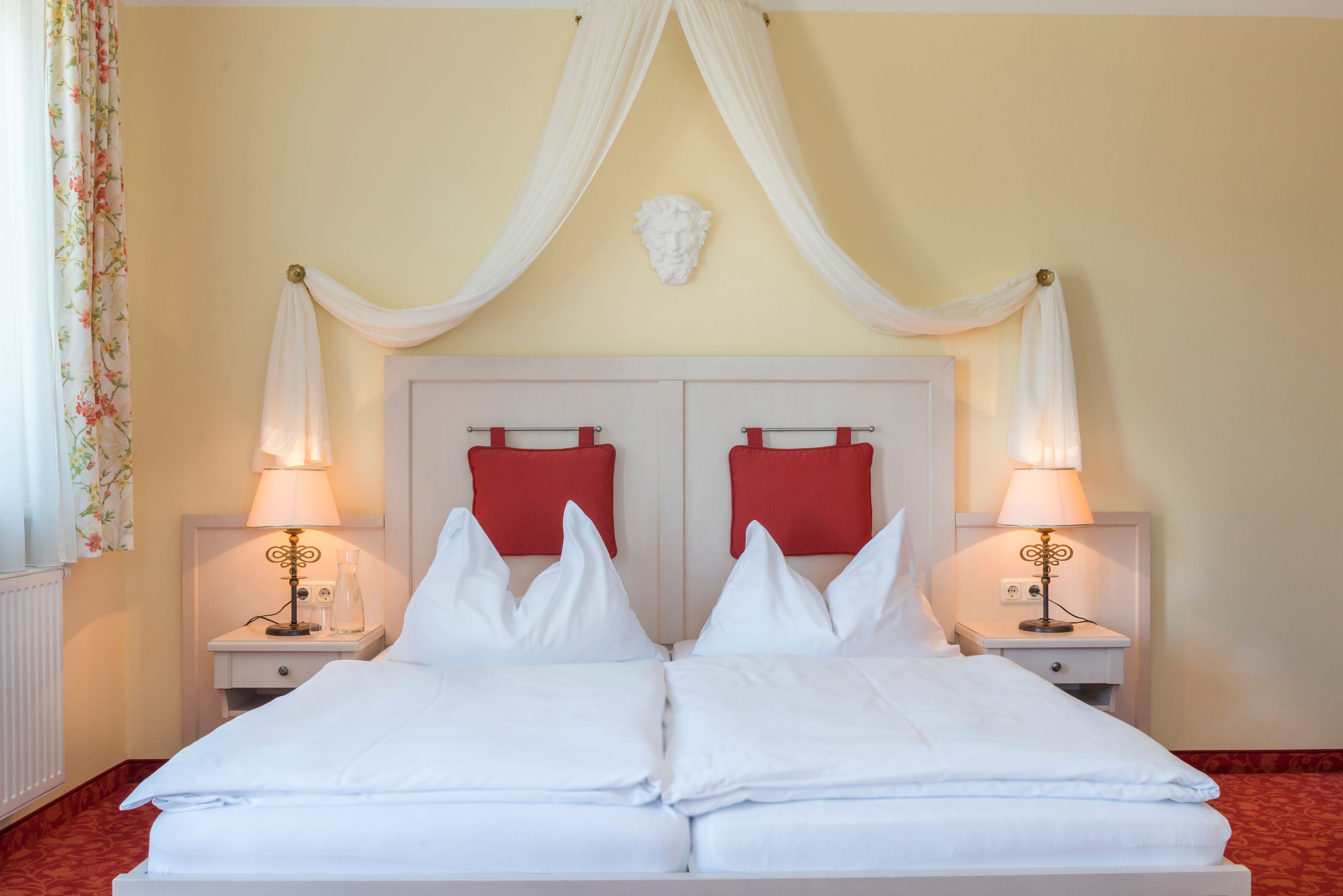 Zimmeransicht mit Himmelbett und roten Polstern