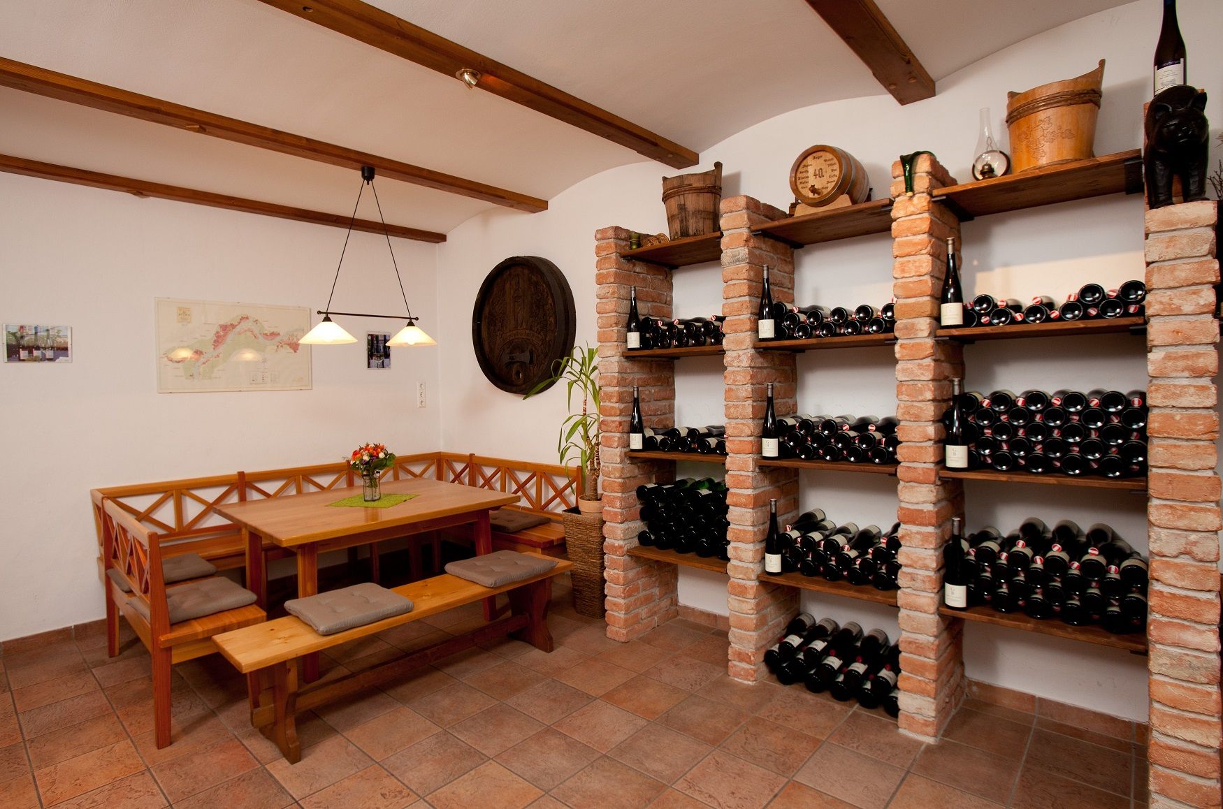 Ein Weinkeller mit einem Tisch und Bänken zur Verkostung, umgeben von Weinregalen voller Flaschen.