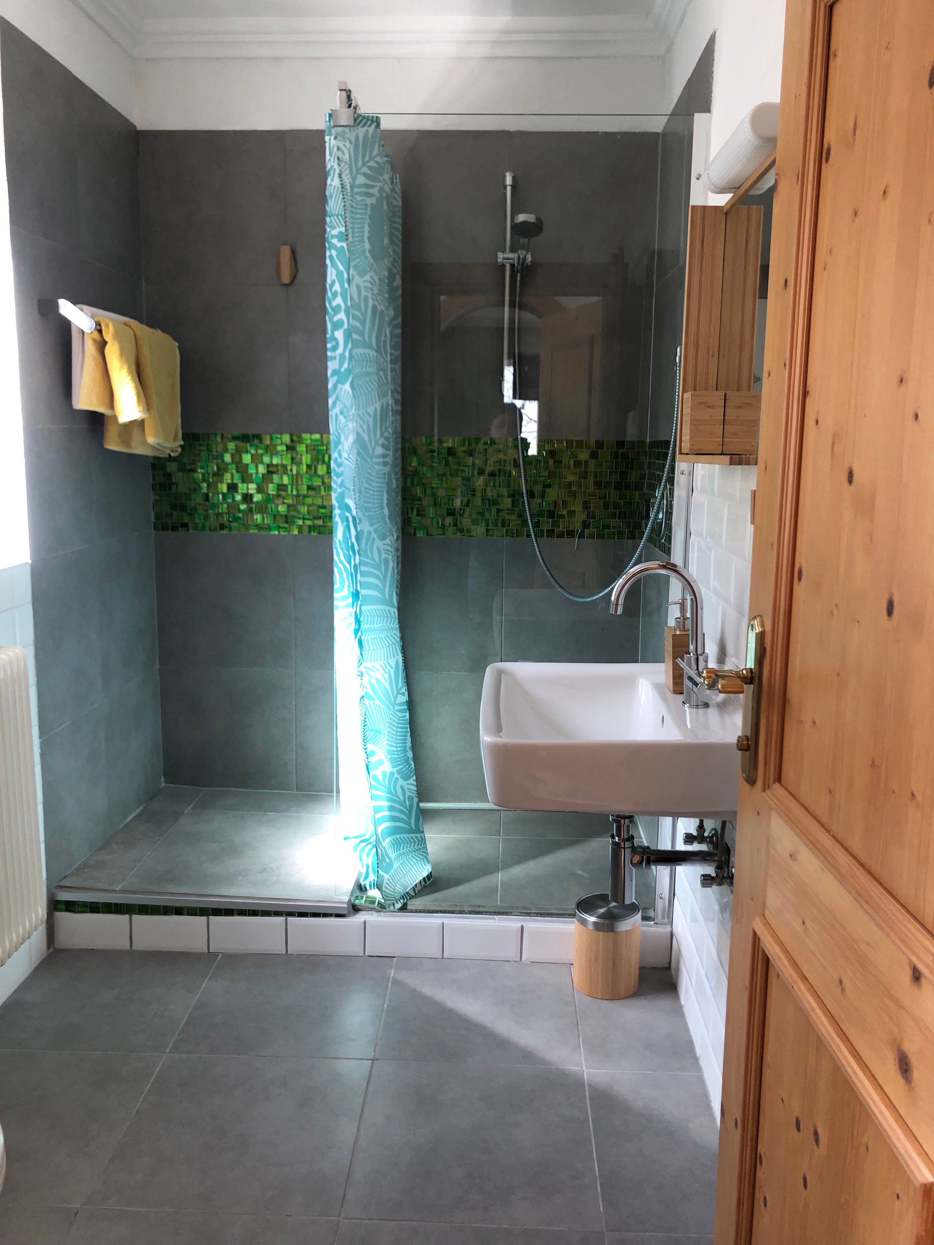 Modernes Badezimmer mit Dusche, Waschbecken und blauen Duschvorhang.
