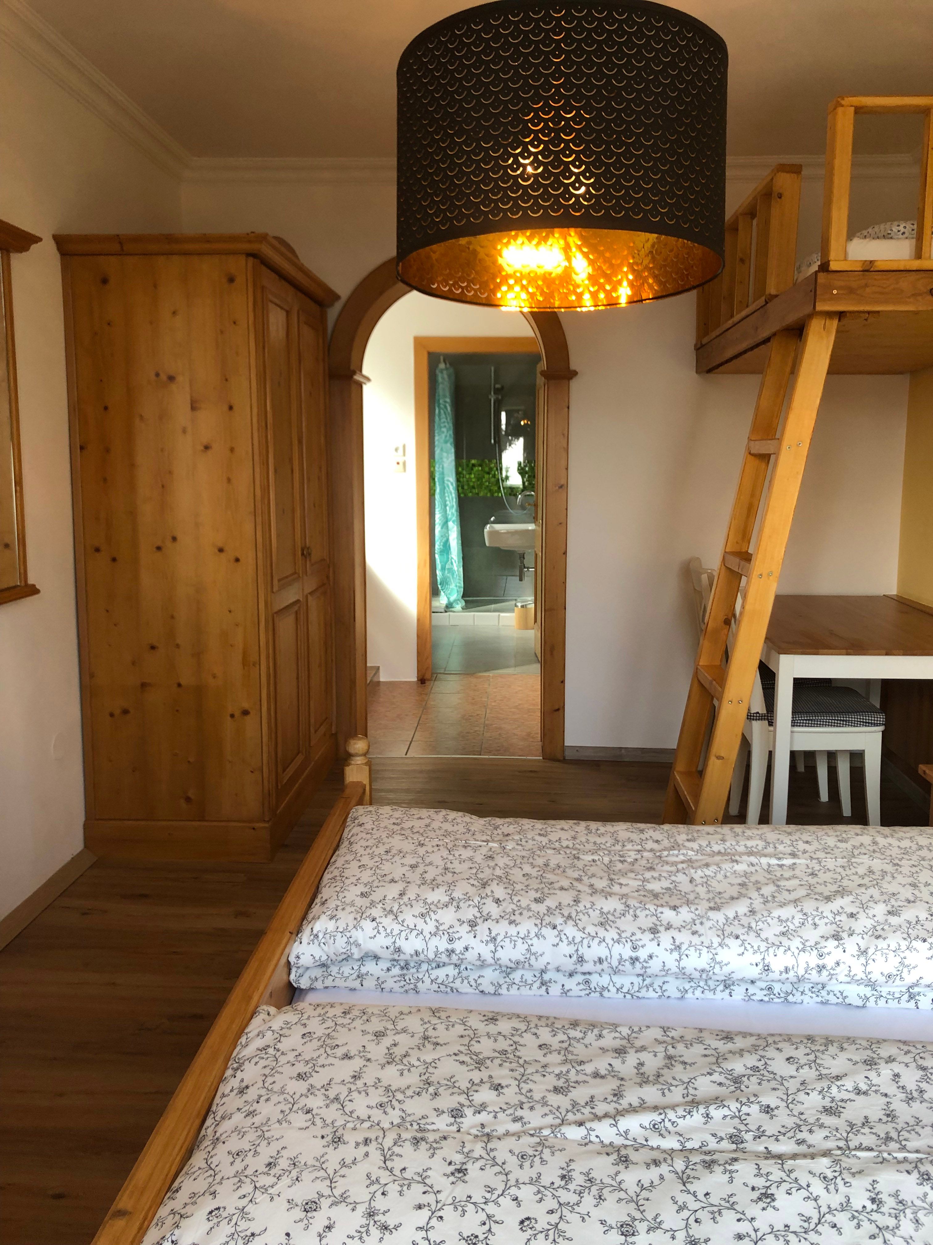 Innenansicht eines Zimmers mit Holzmöbeln und einem Durchgang zu einem Badezimmer.