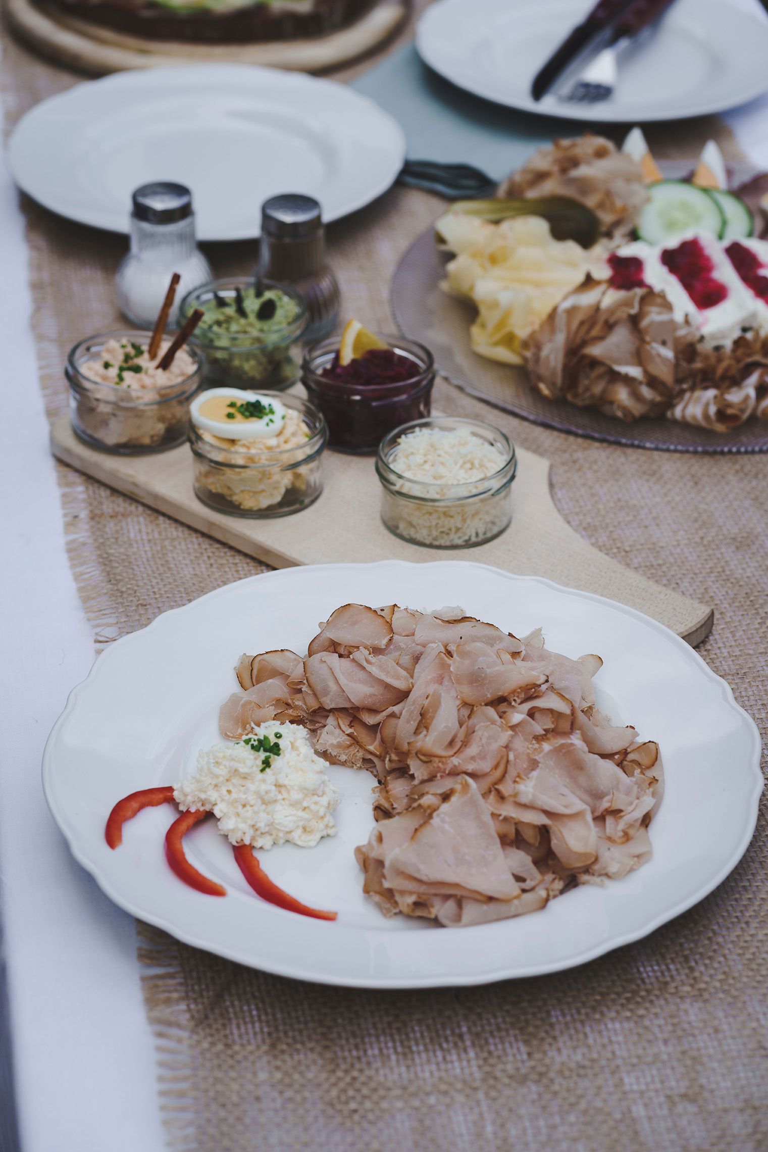 A plate with cold cuts and side dishes on a table.