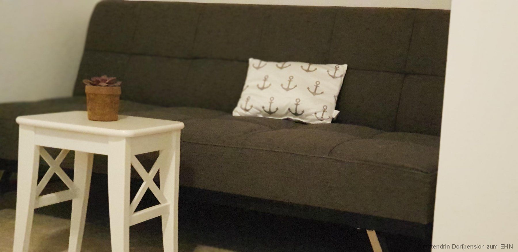 Graues Sitzsofa mit weißem Tisch.