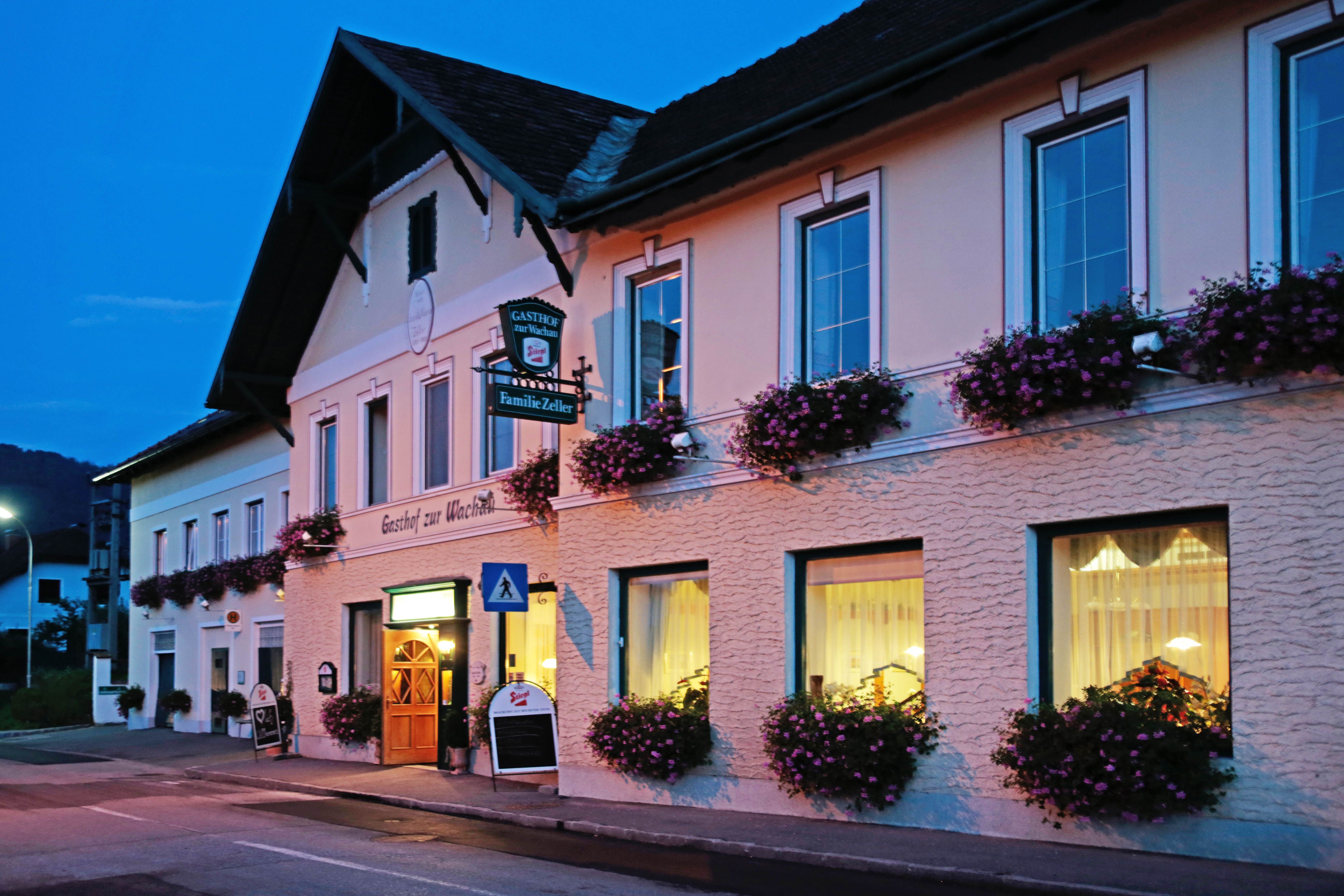 Ein traditionelles Gasthaus mit Blumen geschmückten Fenstern bei Dämmerung.