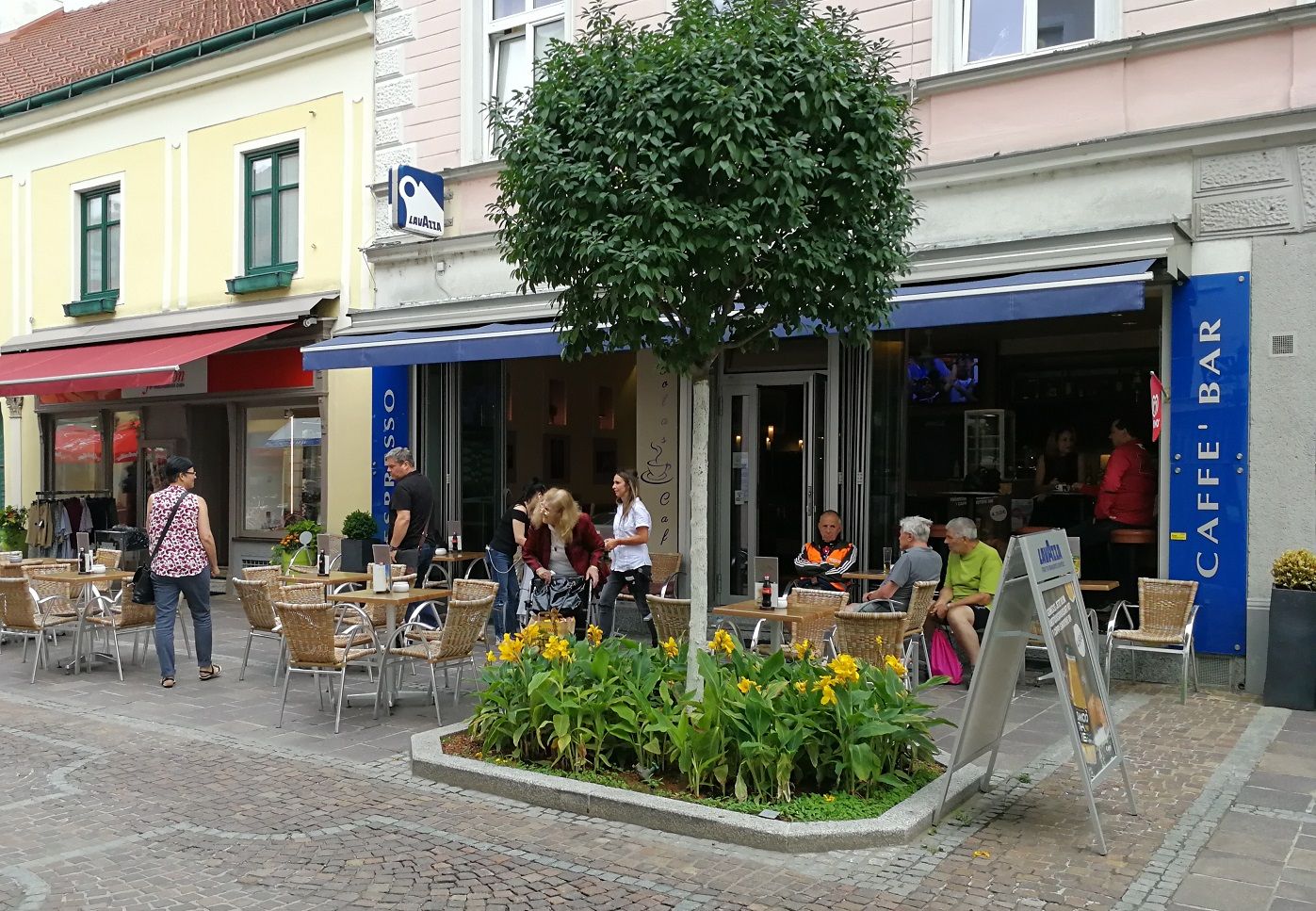 Kaffeehaus von außen mit blauer Markise und Baum davor