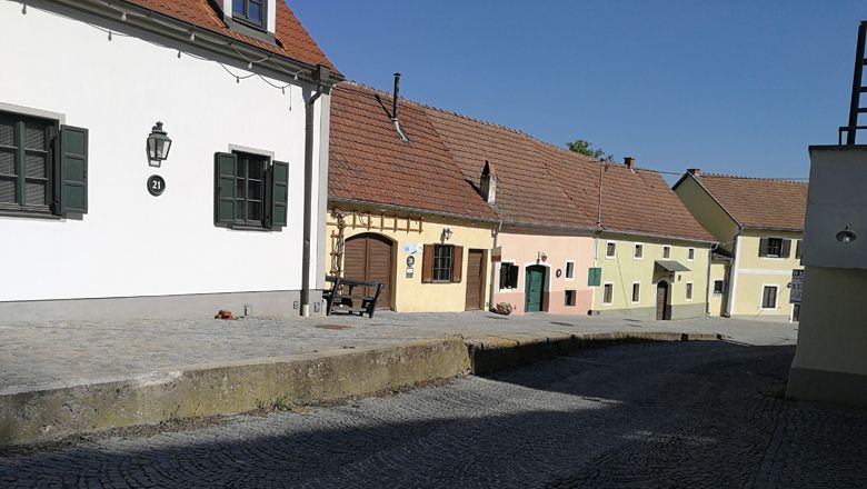 Bunte Häuser in der Rohrendorfer Kellergasse bei sonnigem Wetter.