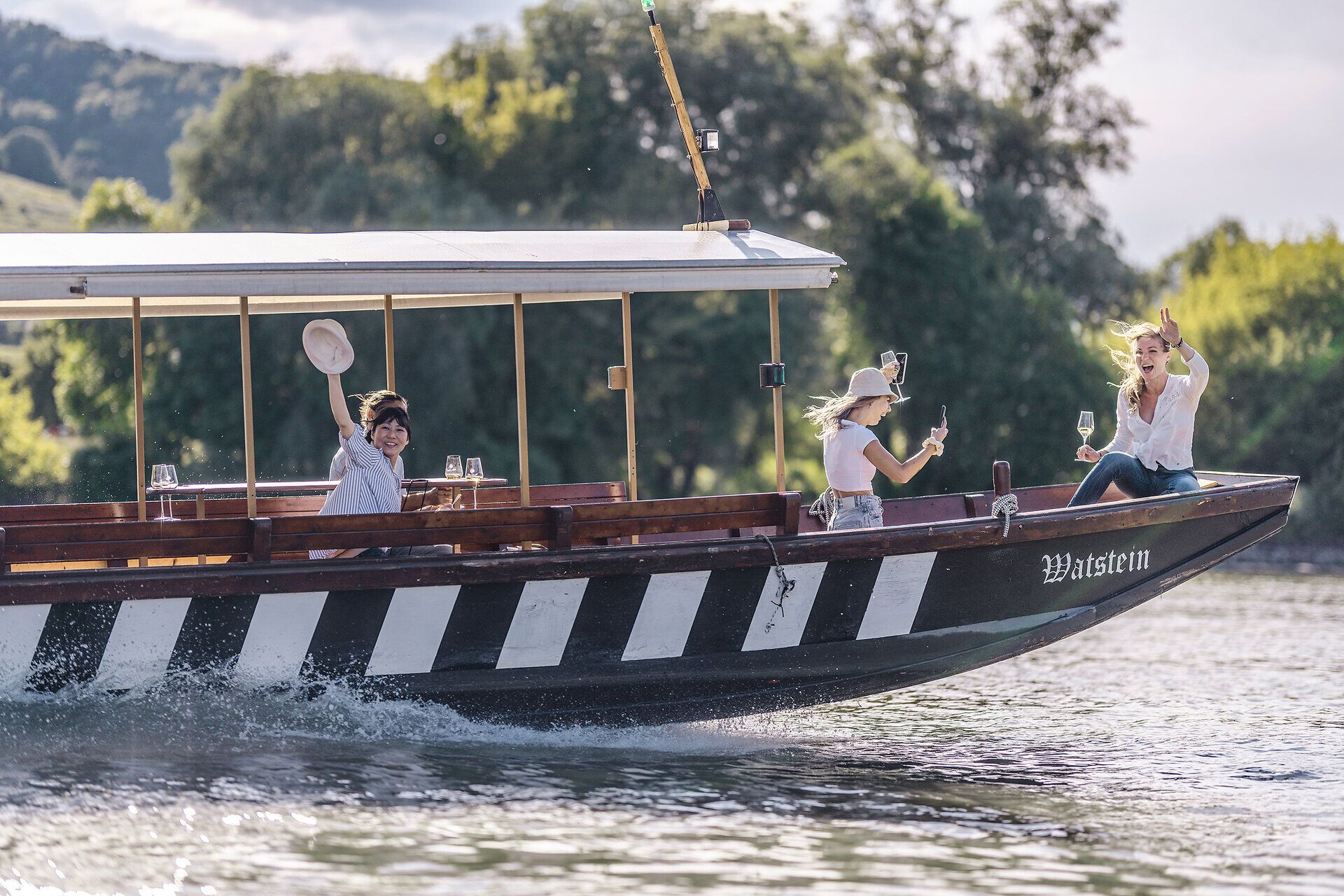 Zwei Mädchen winken von einer Holzzille.