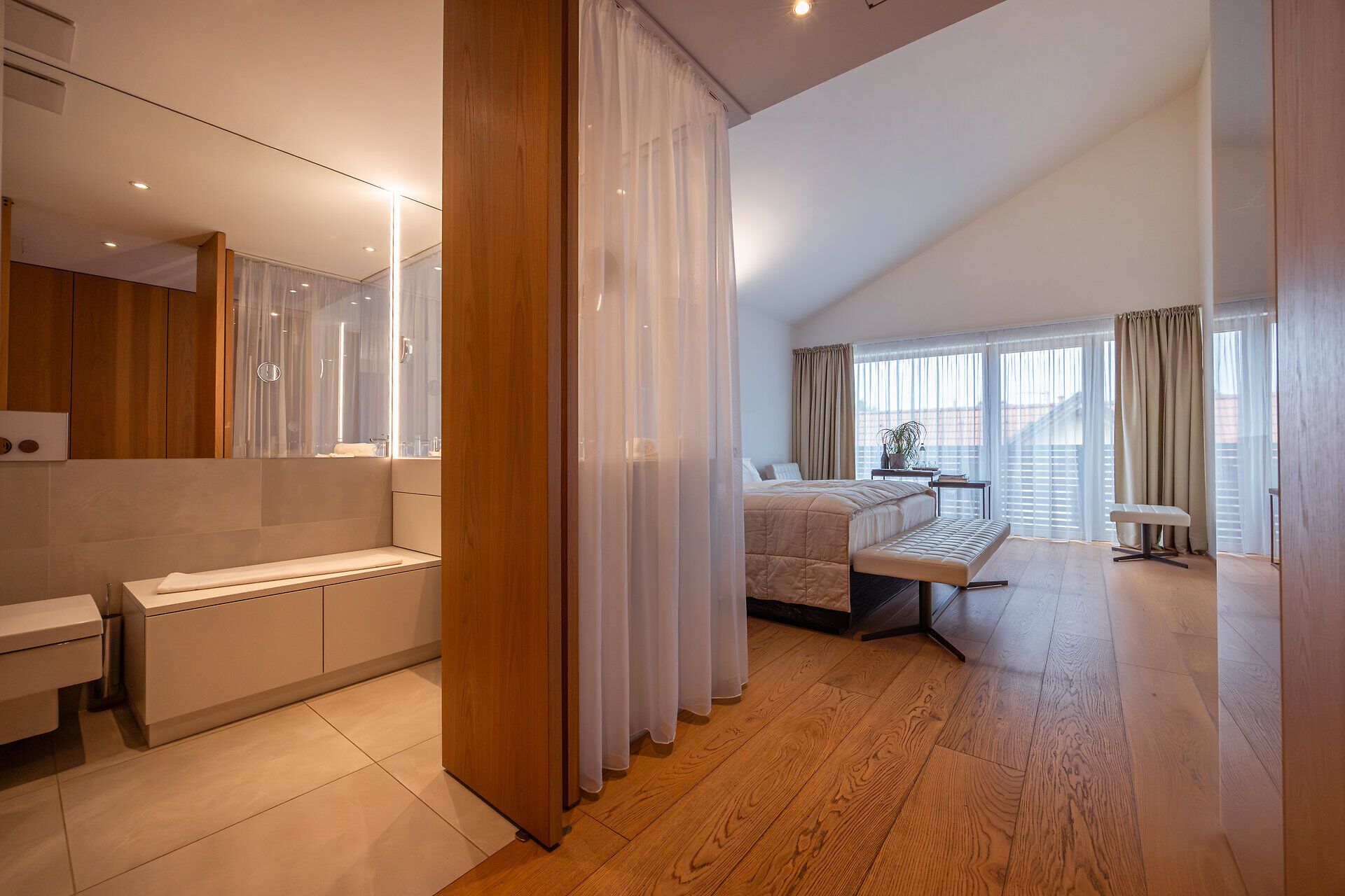 In diesem eleganten Raum vereinen sich modernes Design und gemütliche Atmosphäre. Große Fenster lassen das Licht hereinströmen und bieten einen Blick auf die umliegende Natur, während die sanften Farben der Einrichtung zur Entspannung einladen.