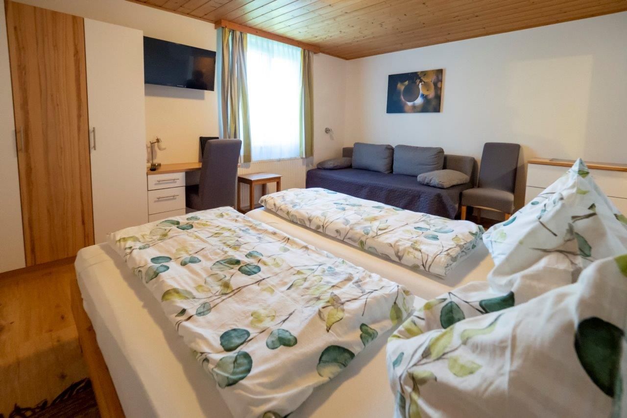 Gemütliches Gästezimmer mit Doppelbett, Sofa, Schreibtisch und TV.