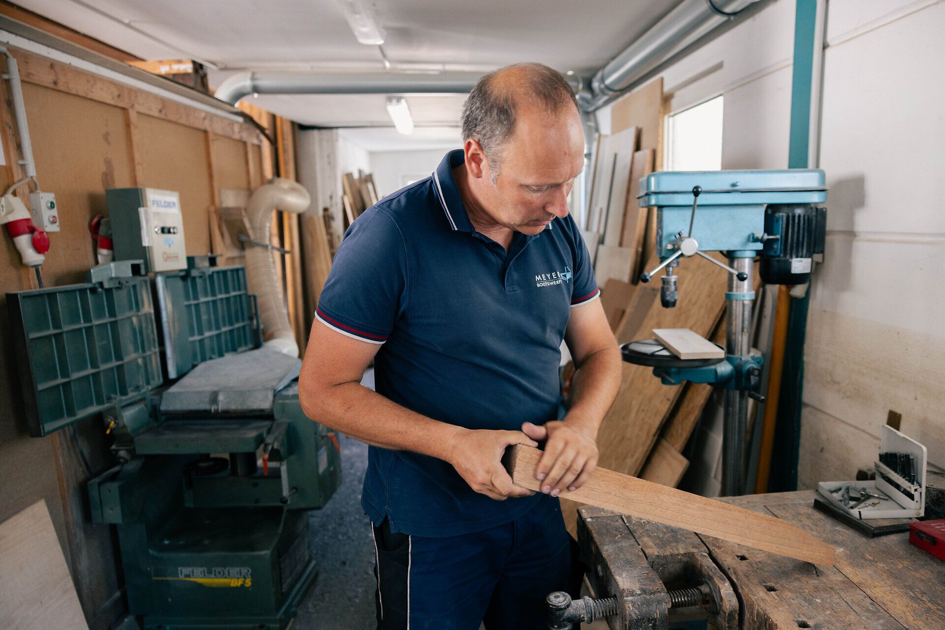 Ein Mann arbeitet in der Werft an einem Stück Holz.