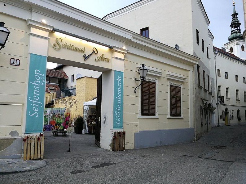 Eingang zum Schlüsselamt mit Schildern für Seifenshop und Geschenkemarkt.