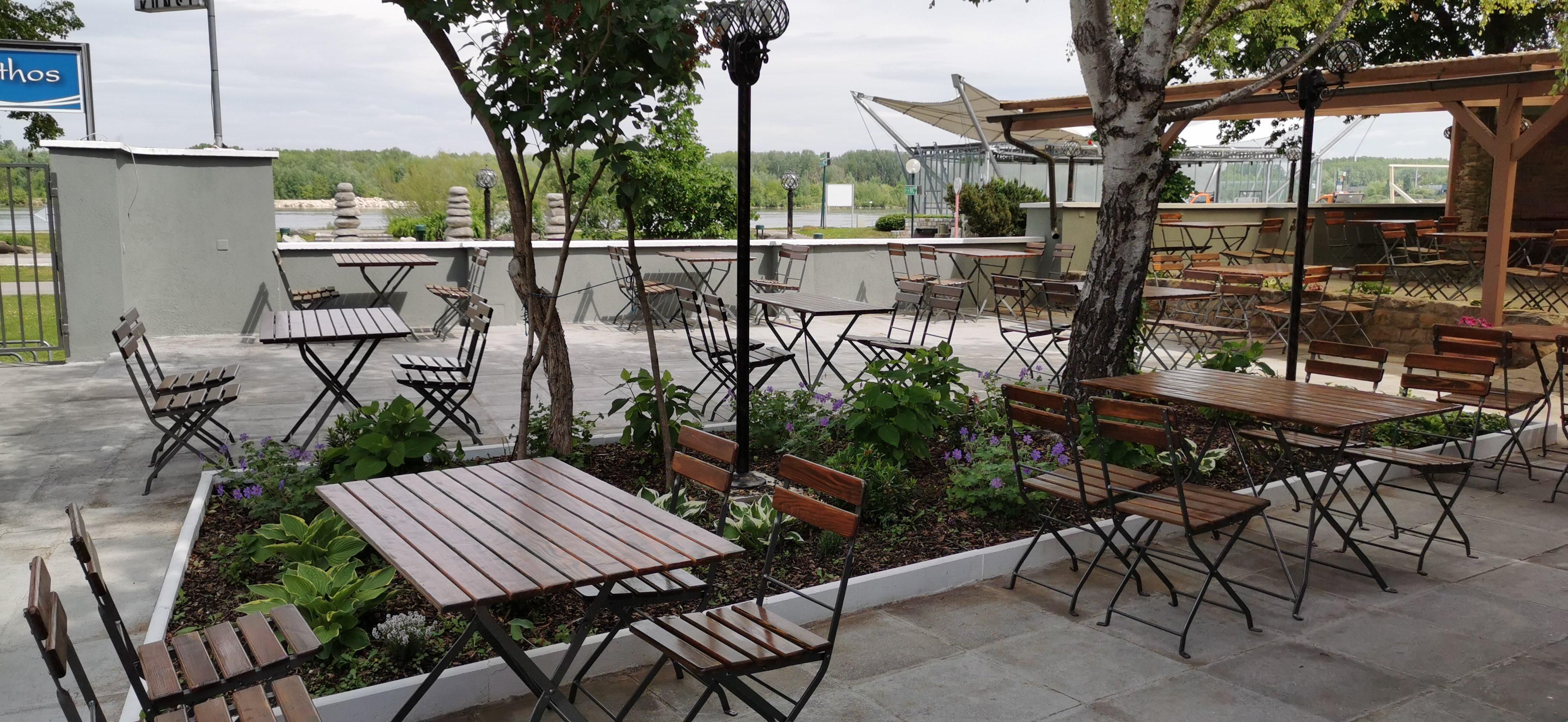 Gastgarten mit Sitzmöbeln im Hintergrund die Donau 