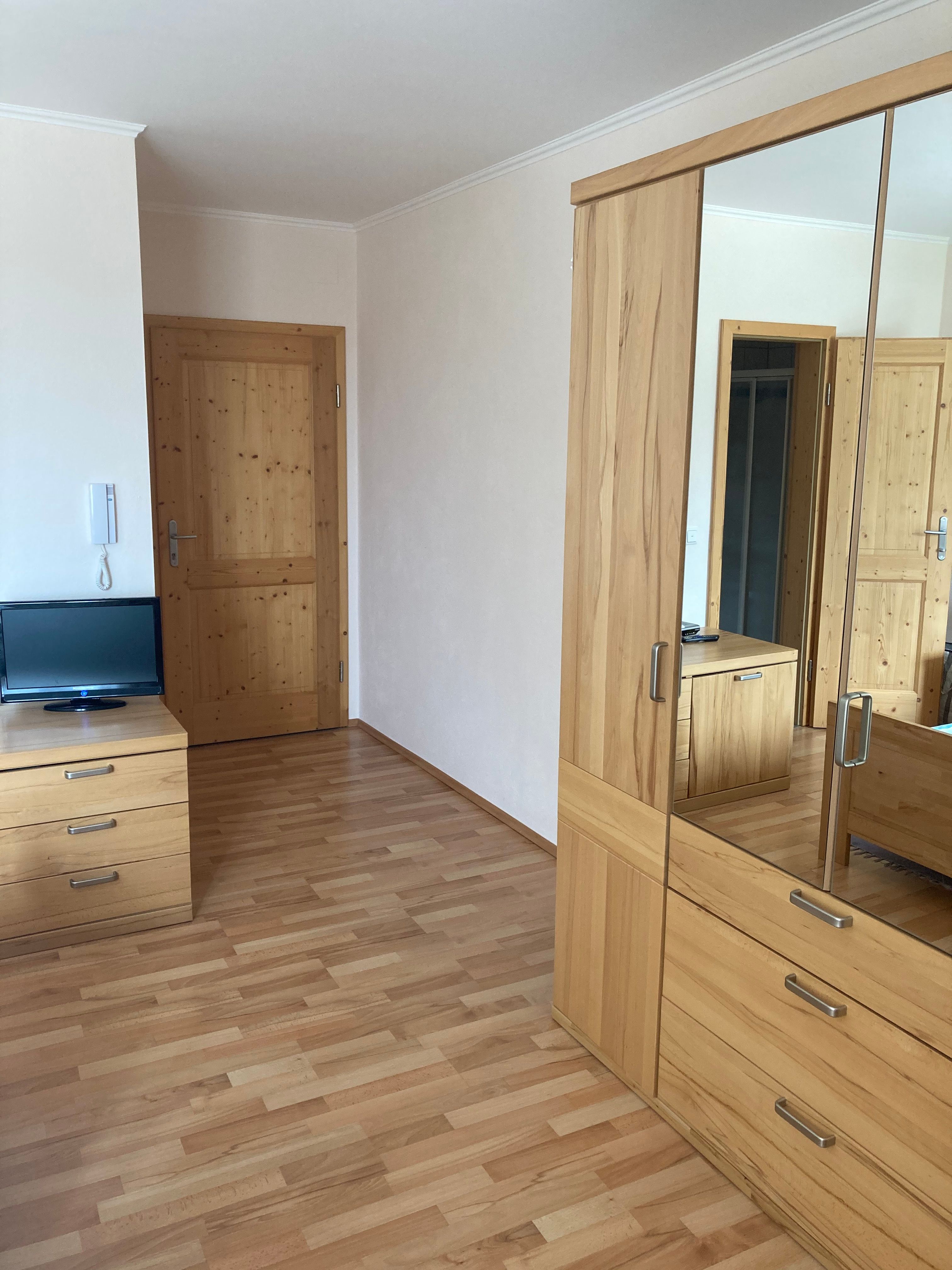 Zimmertüre mit Schrank und Spiegel und einem kleinen Fernseher.