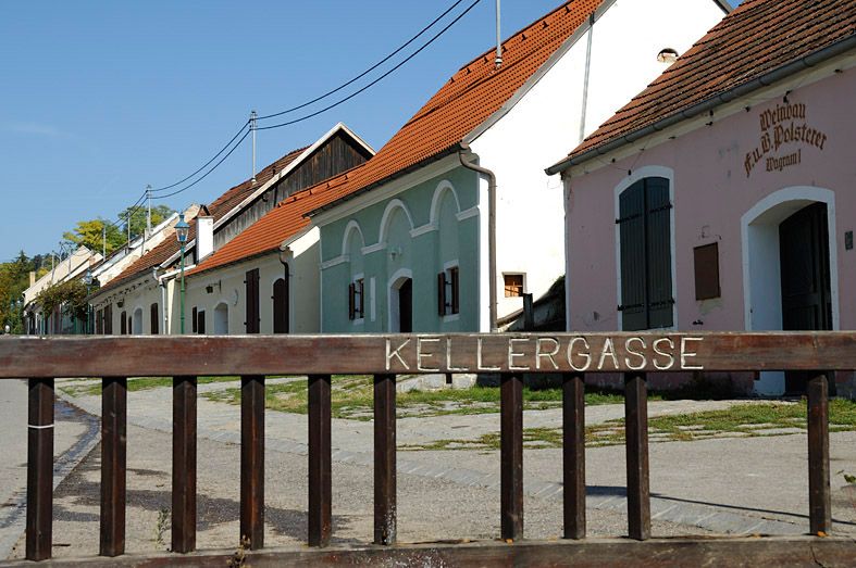 Historische Kellergasse in Grafenwörth mit bunten Gebäuden und einem Holzzaun im Vordergrund.