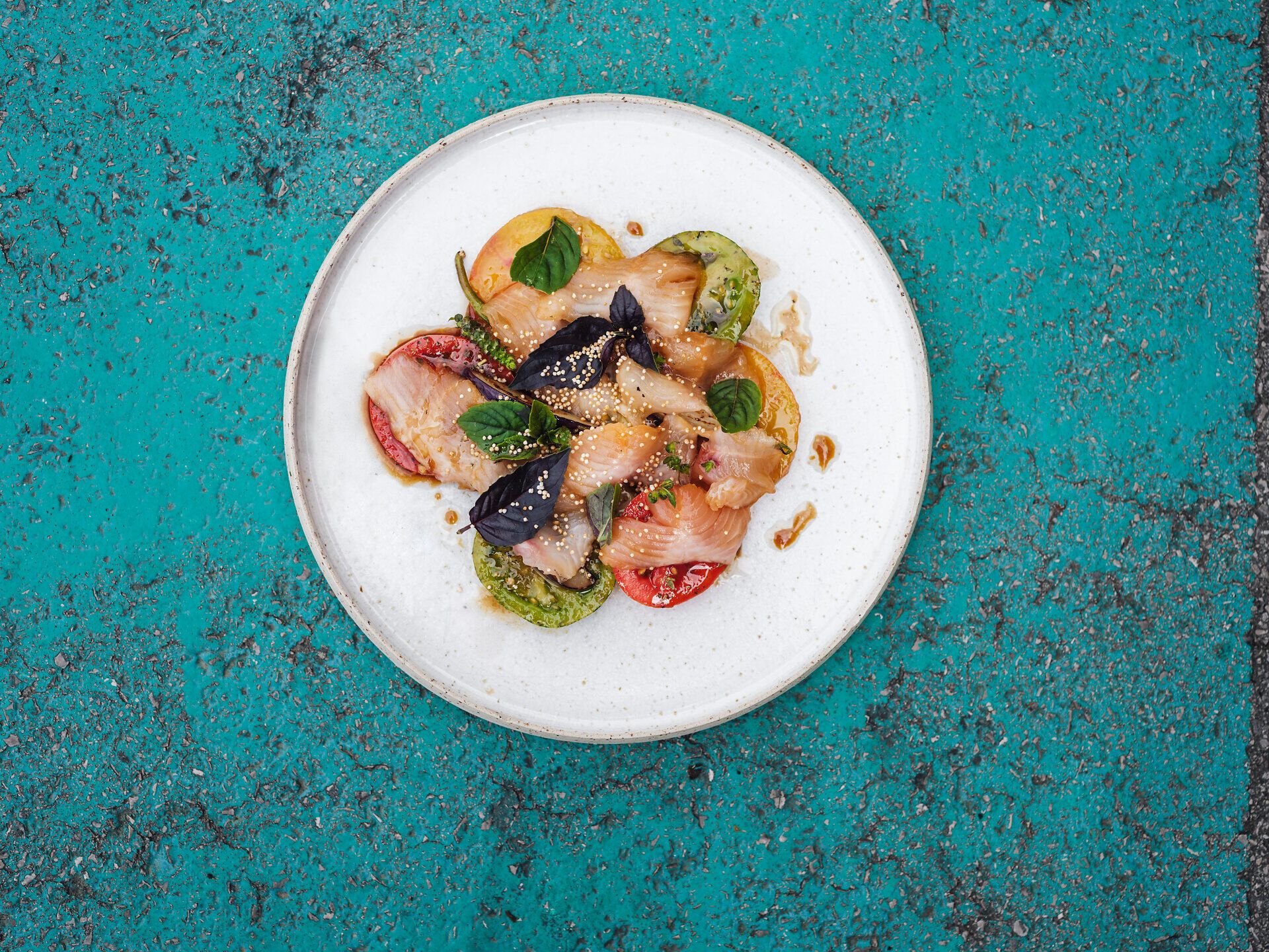 Speisenteller mit Fisch, Avocado und grünen Kräutern garniert