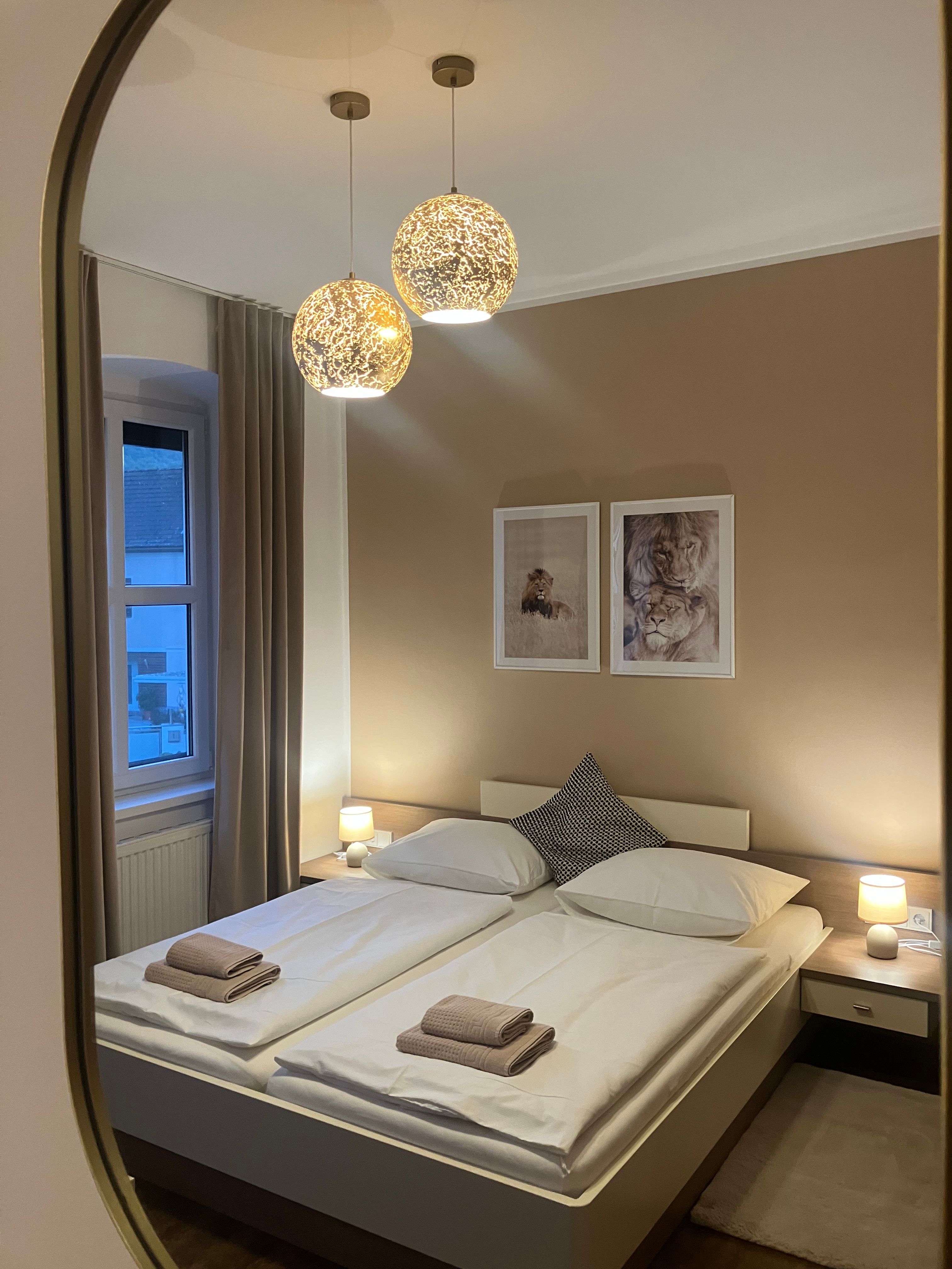 A cozy double room with two beds, decorative lamps and pictures on the wall.