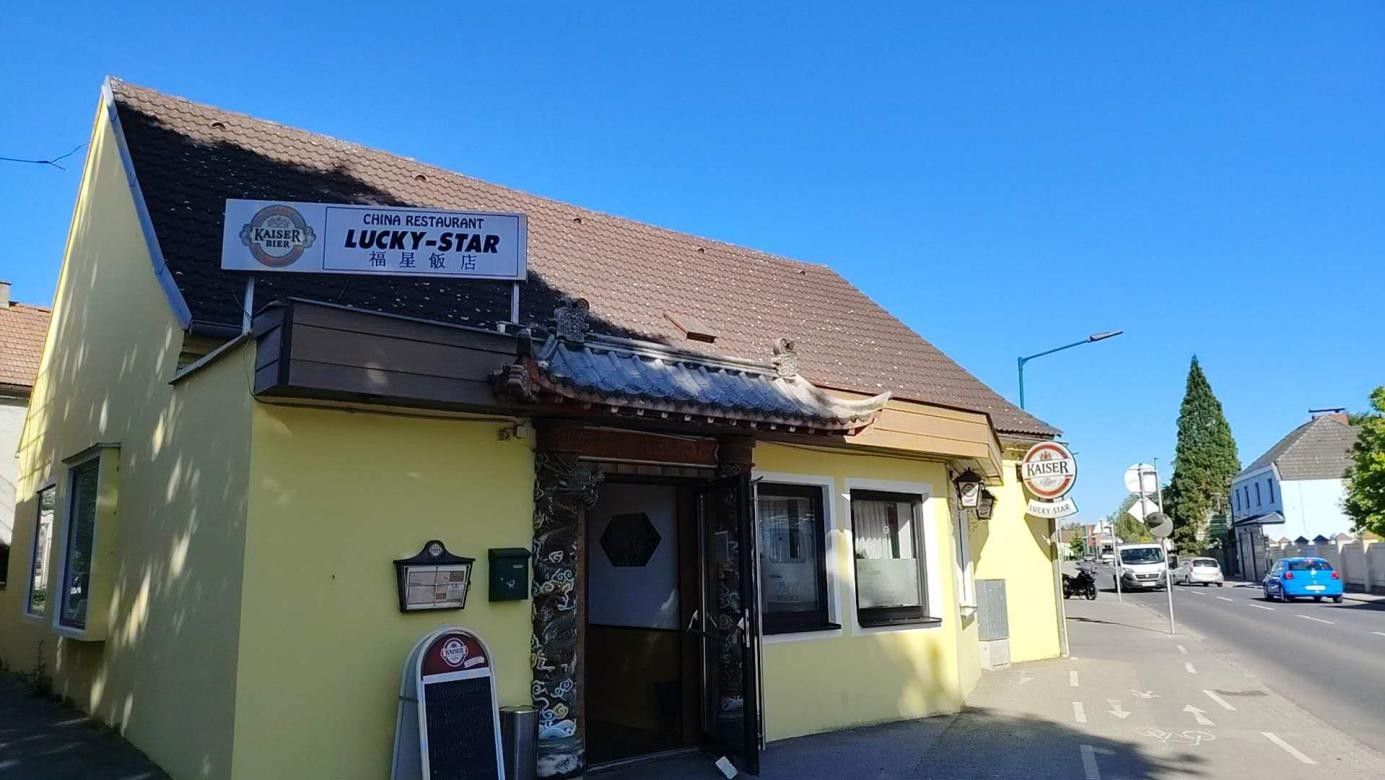 Egy sárga épület külső nézete a "China Restaurant Lucky-Star" felirattal.