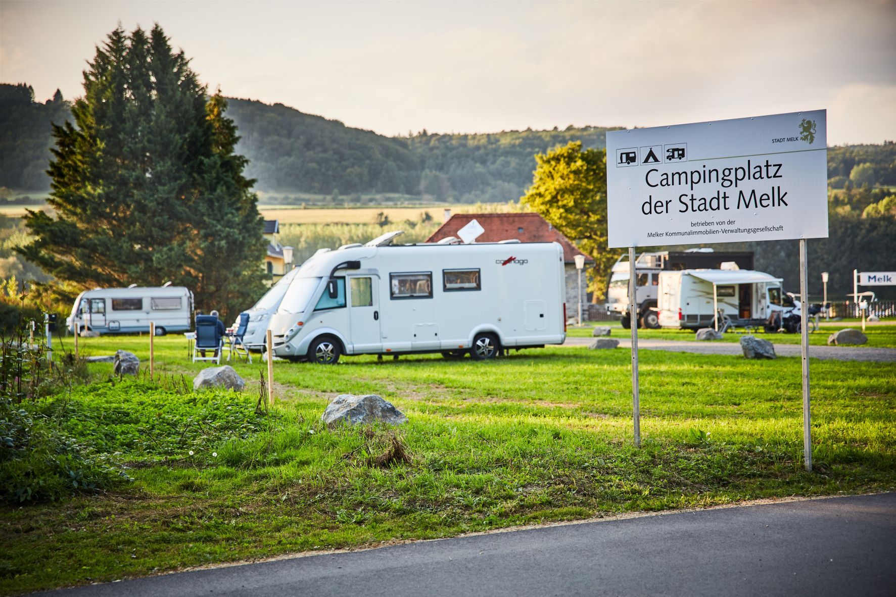 Campingplatz in Melk mit Wohnmobilen und einem Schild im Vordergrund.