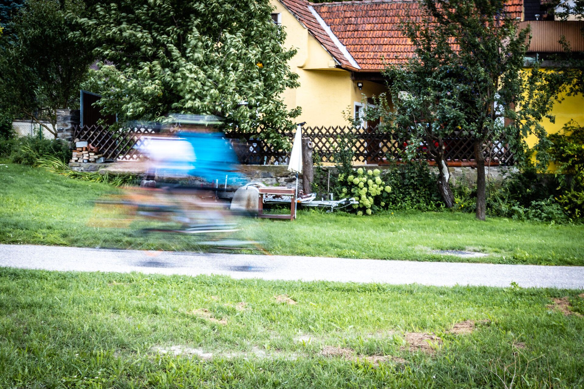 Blauer Radfahrer als Schatten vor einem gelben Haus.