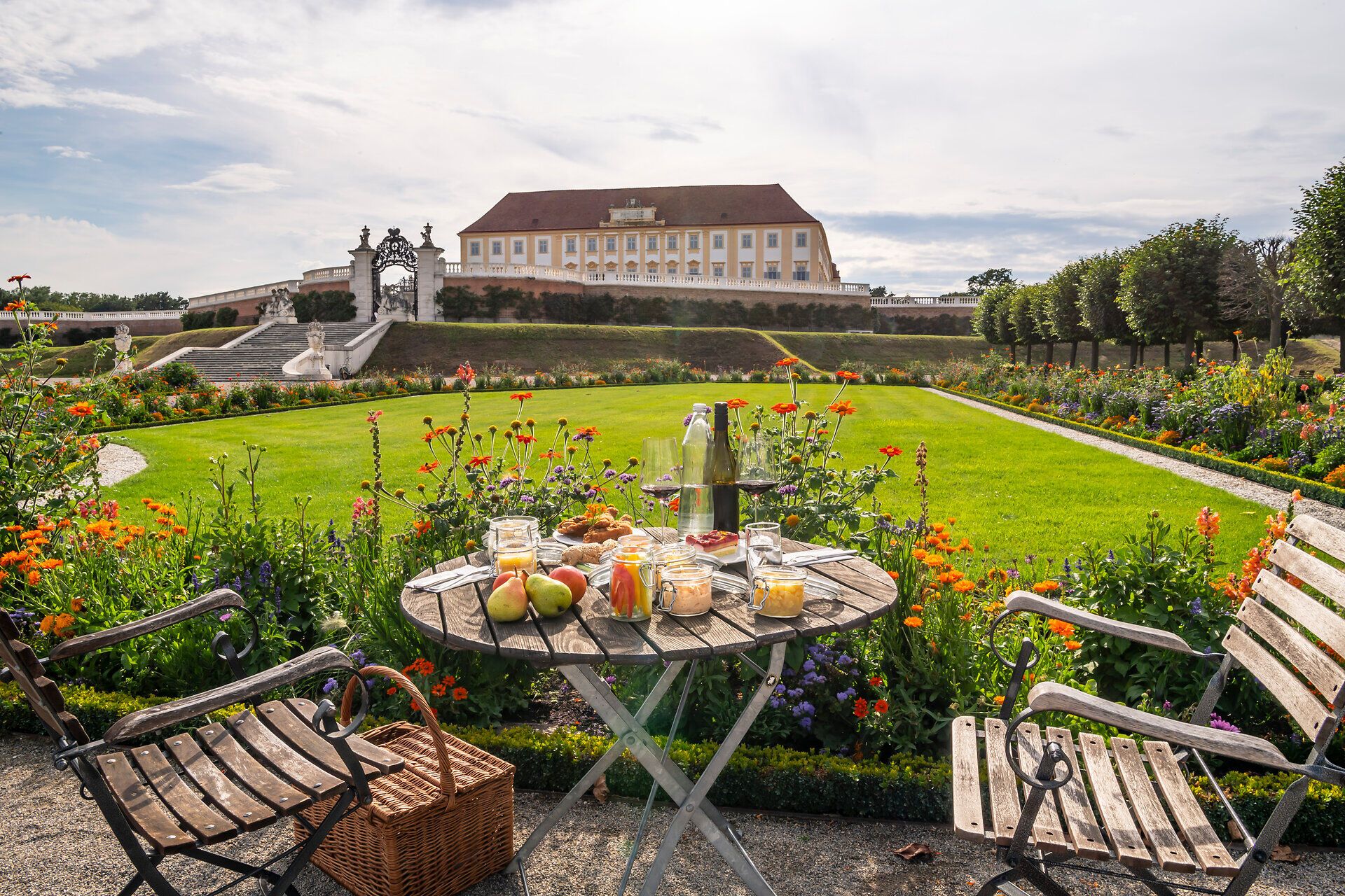 Ein idyllisches Picknick im Frühling, umgeben von blühenden Blumen und einer malerischen Landschaft. Die sanften Farben der Natur und der Duft frischer Früchte laden dazu ein, die Seele baumeln zu lassen und die Schönheit des Moments zu genießen.