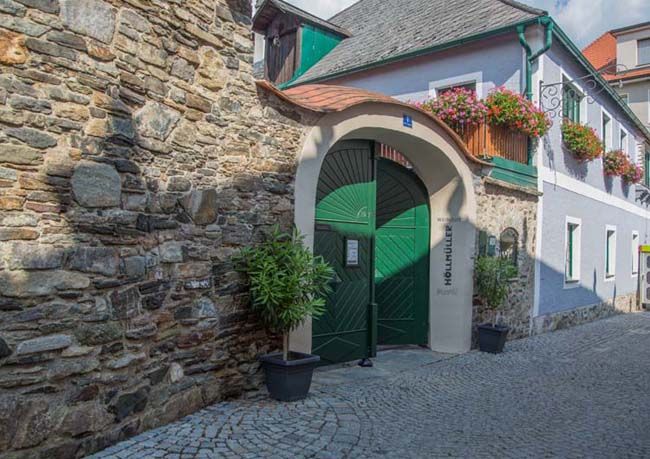 Historisches Gebäude mit grünem Tor und Blumen.