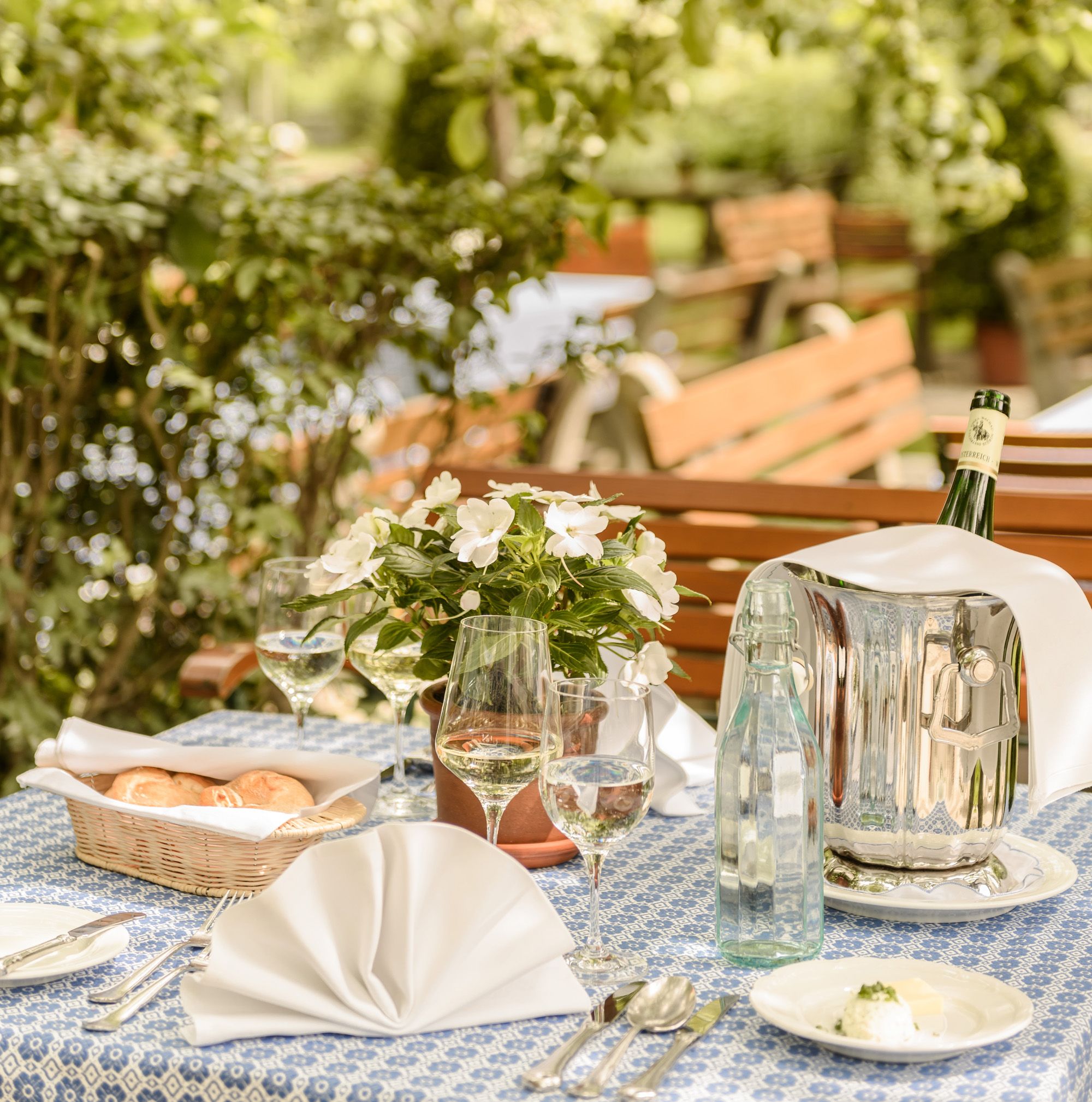 Reich gedeckter Tisch mit einem Sektkühler und Flasche Wein und Brotkörberl