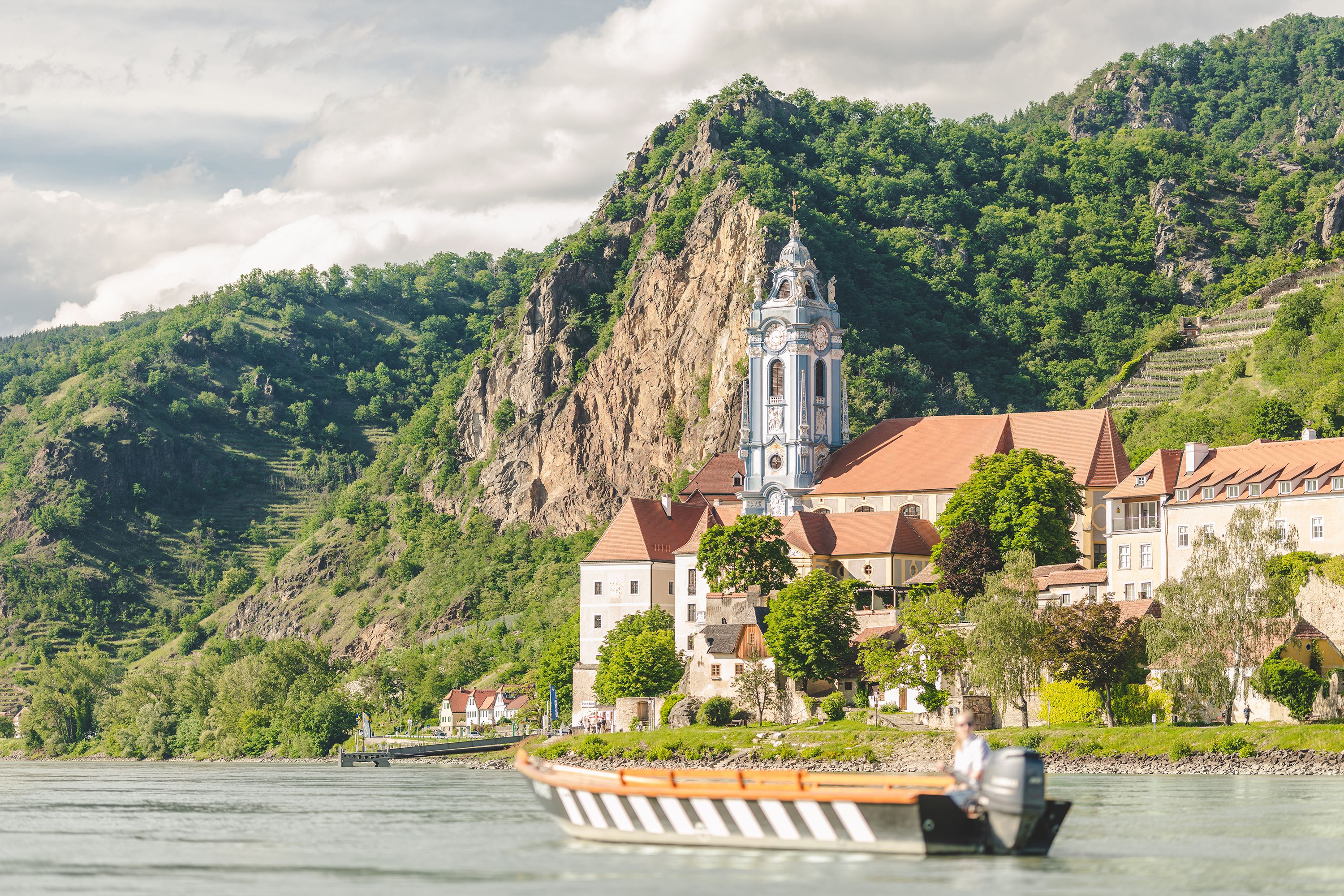 Eine Holzzille auf dem Wasser vor dem blauen Turm von Dürnstein.