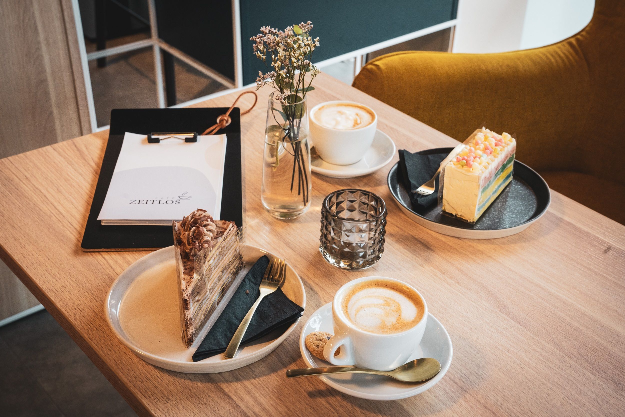 Café-Tisch mit zwei Kuchen und Cafés mit Speisekarte und Blume.