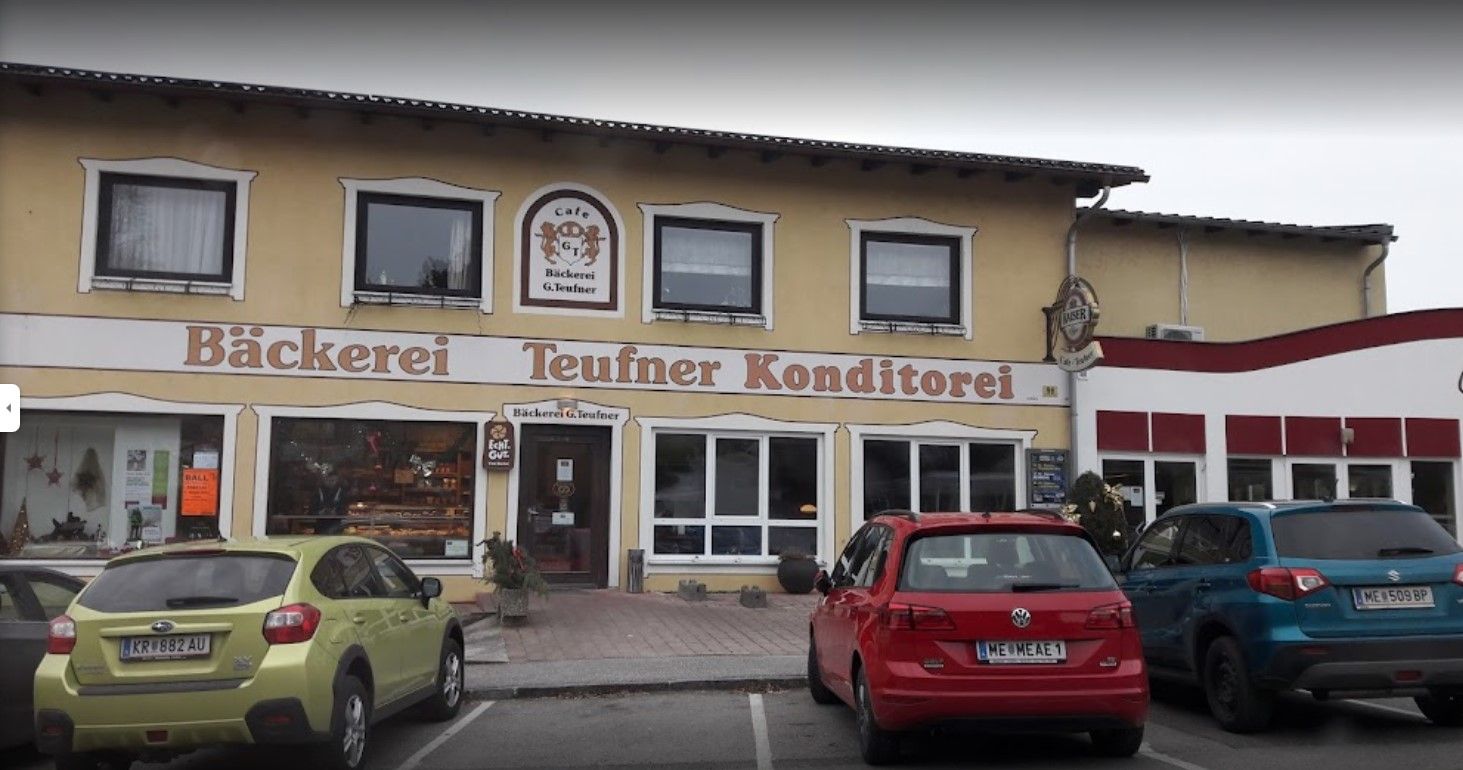 Außenansicht der Bäckerei Teufner mit geparkten Autos davor.