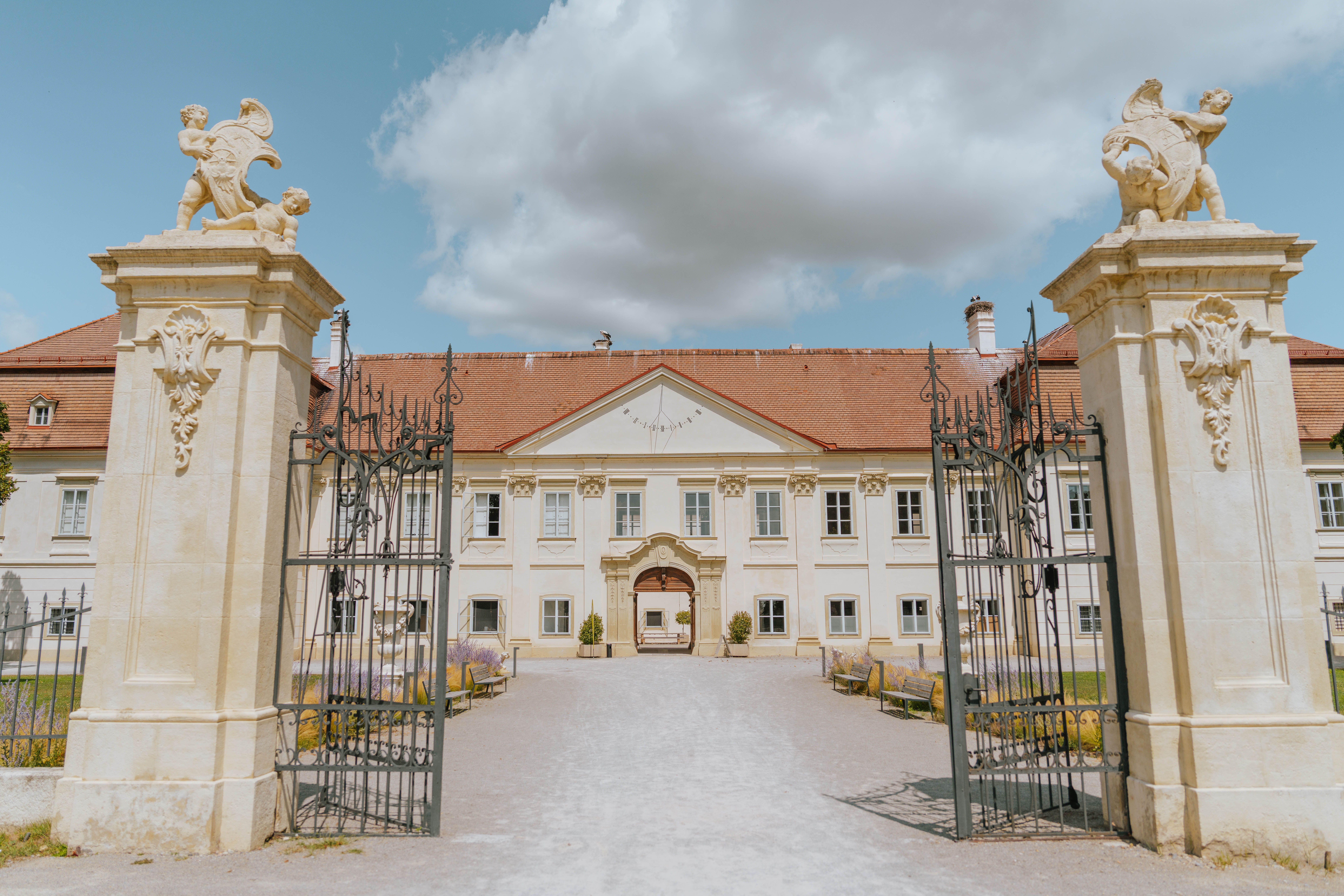 Eingangstor und Fassade von Schloss Marchegg unter blauem Himmel.