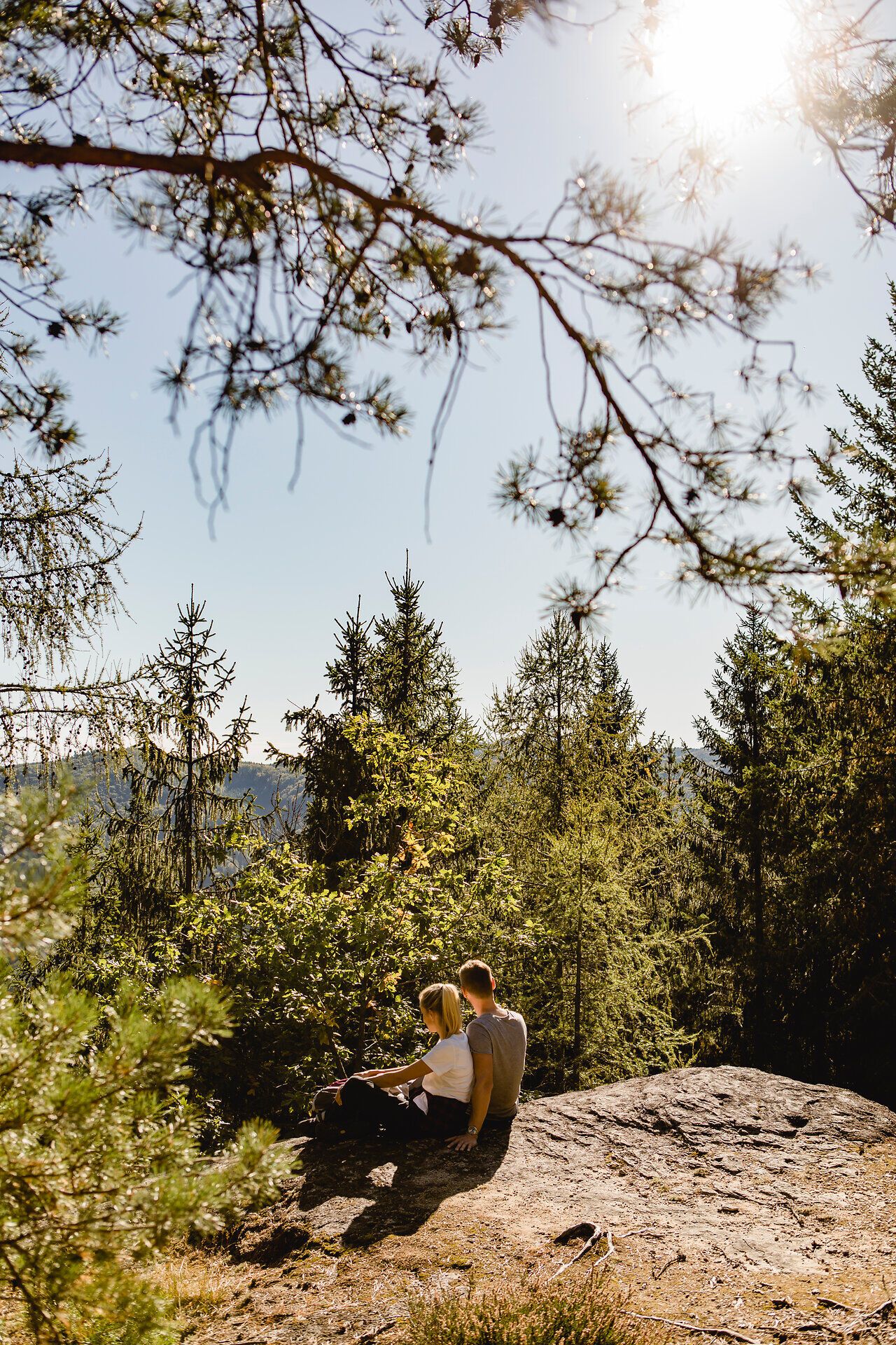 Ein Pärchen sitzt auf einem Felsplateau und blickt in die Ferne.