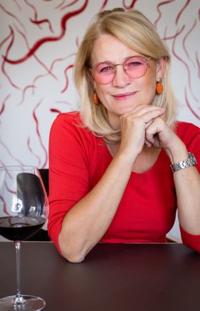 Die Winzerin Dorli Muhr sitzt an einem Tisch und blickt in die Kamera.