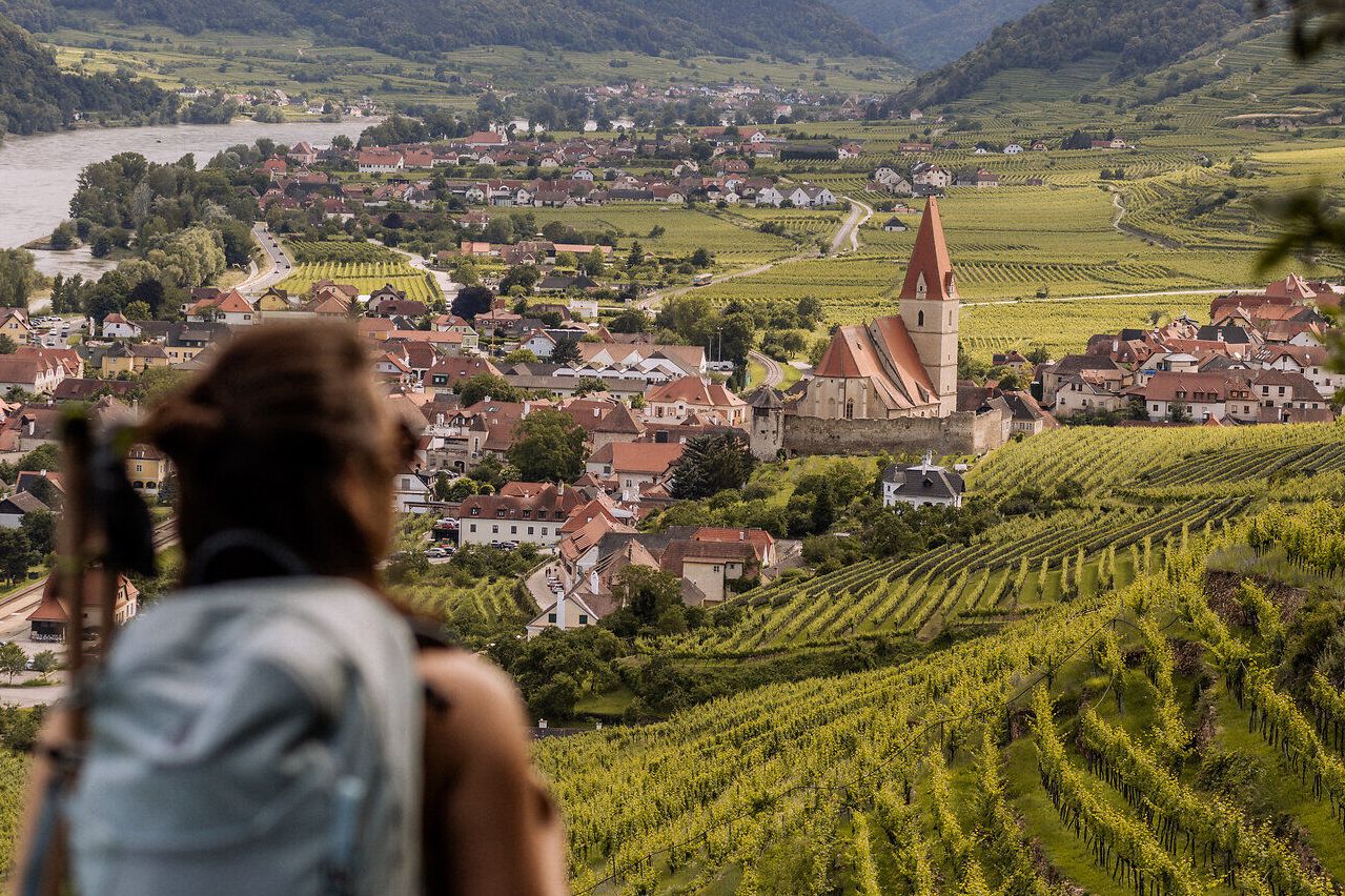 Eine Wanderin mit Rucksack schaut auf Weißenkirchen.