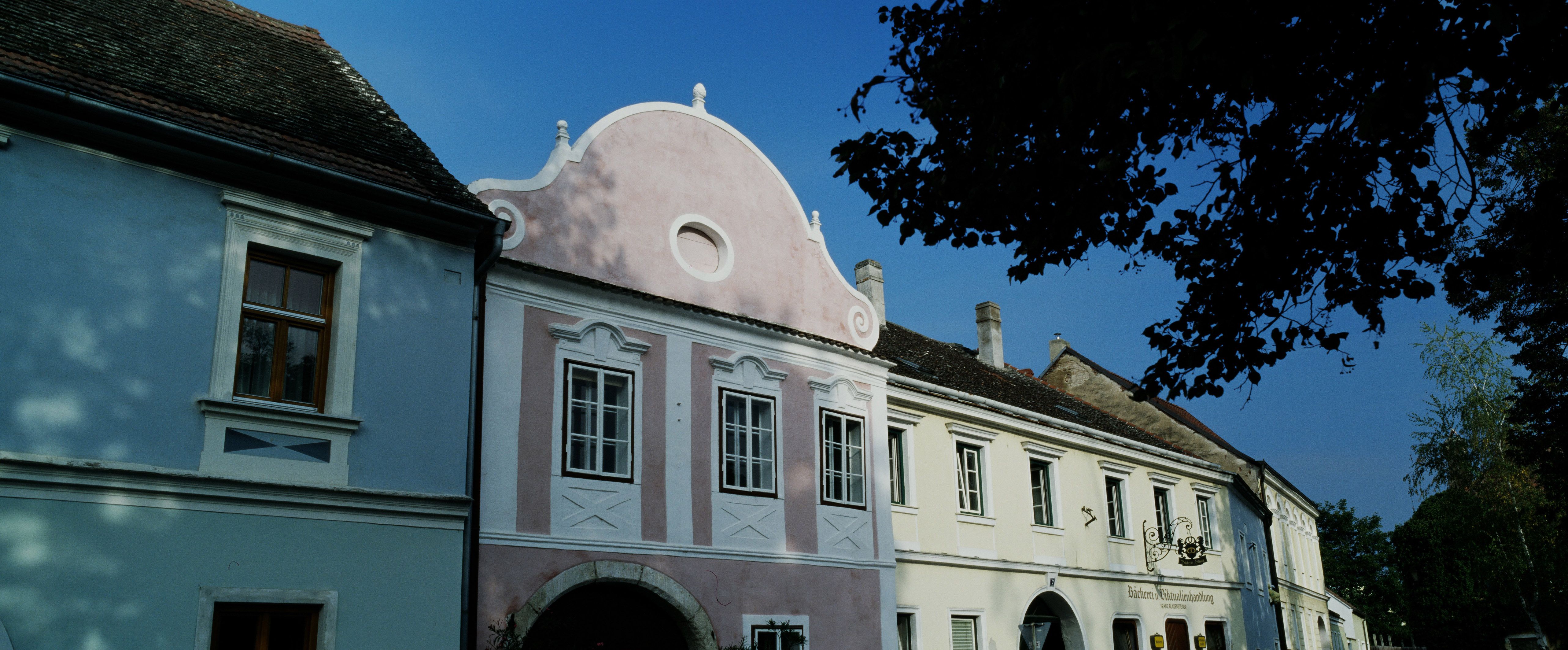 Historische Gebäude in Hadersdorf-Kammern mit blauer und rosa Fassade.
