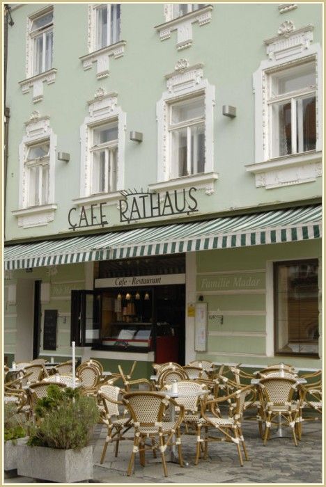 Außenansicht eines Cafés mit Terrasse und gestreifter Markise.