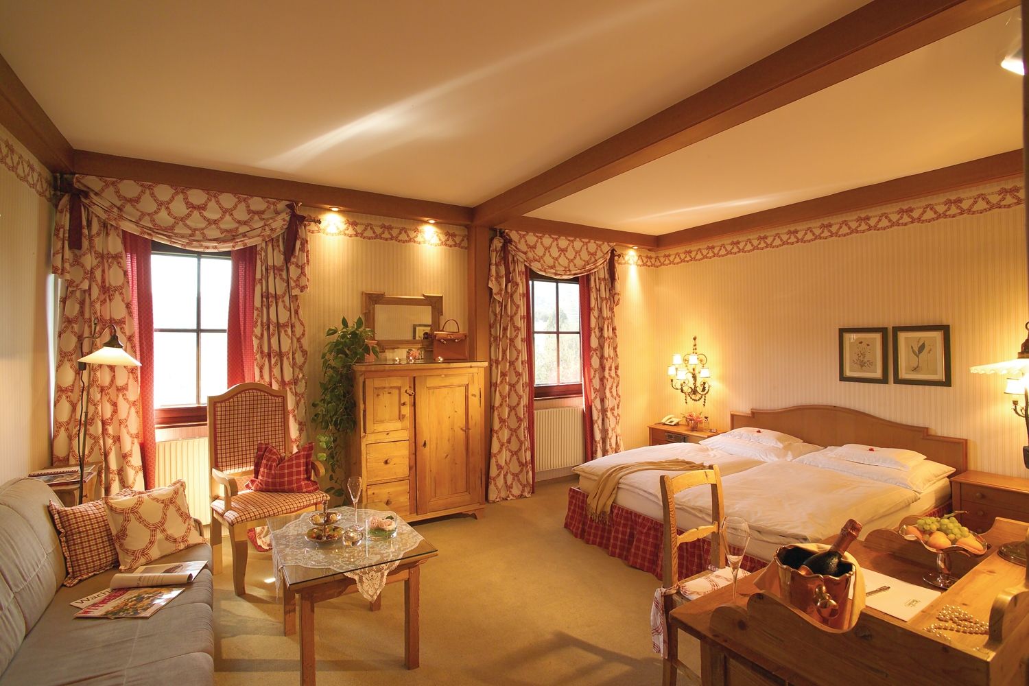 Gemütliches Hotelzimmer im Landhausstil mit Doppelbett, Sofa, Tisch und rustikalen Holzmöbeln.