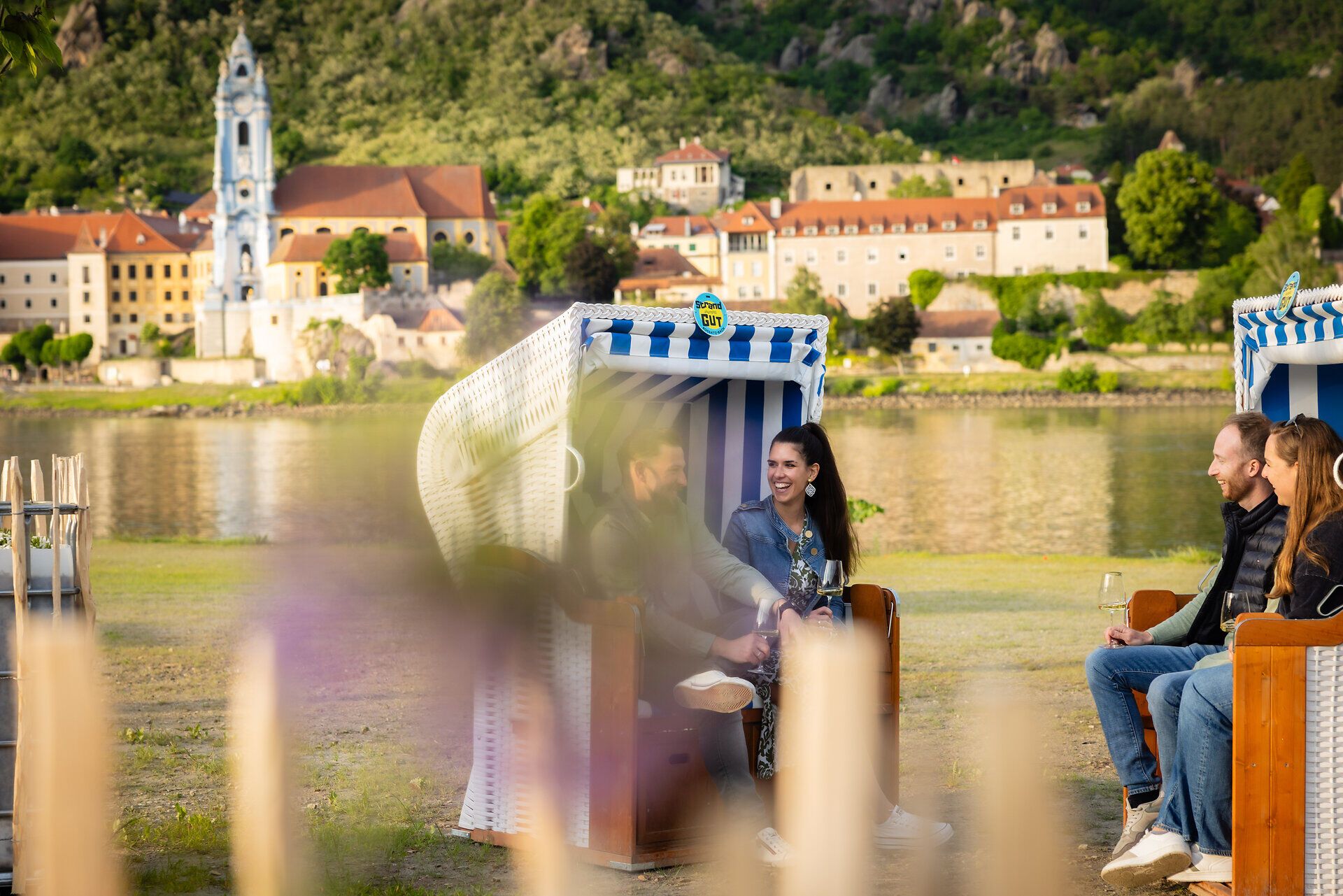 Zwei Pärchen sitzen in Strandkörben gegenüber von Dürnstein