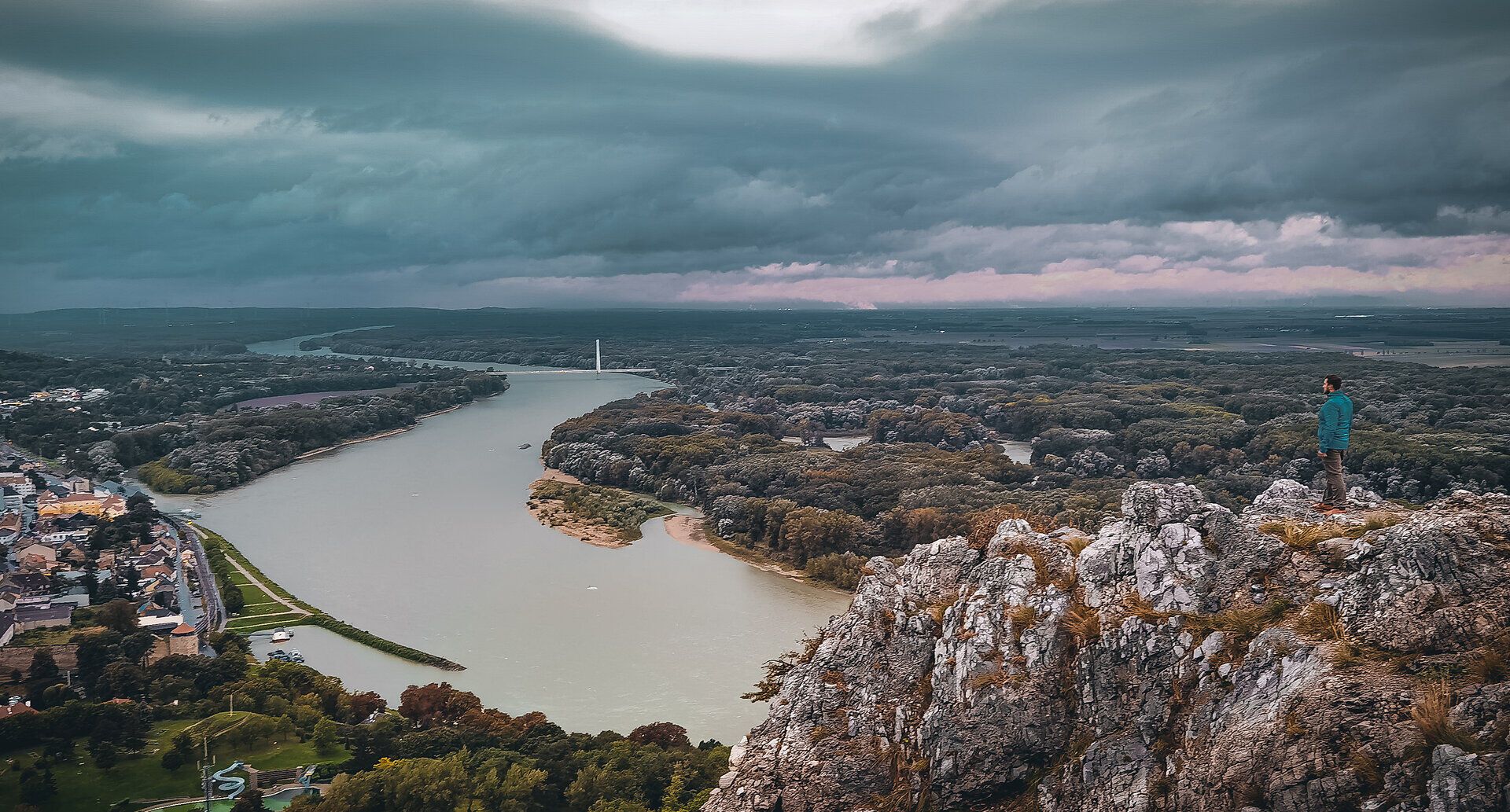 Die sanften Hügel und die majestätische Donau verschmelzen in einem atemberaubenden Herbstpanorama. Die Wolken ziehen dramatisch über den Himmel, während die Farben der Natur in warmen Tönen leuchten. Ein perfekter Ort für Wanderer und Naturliebhaber, um die Schönheit der Landschaft zu genießen.