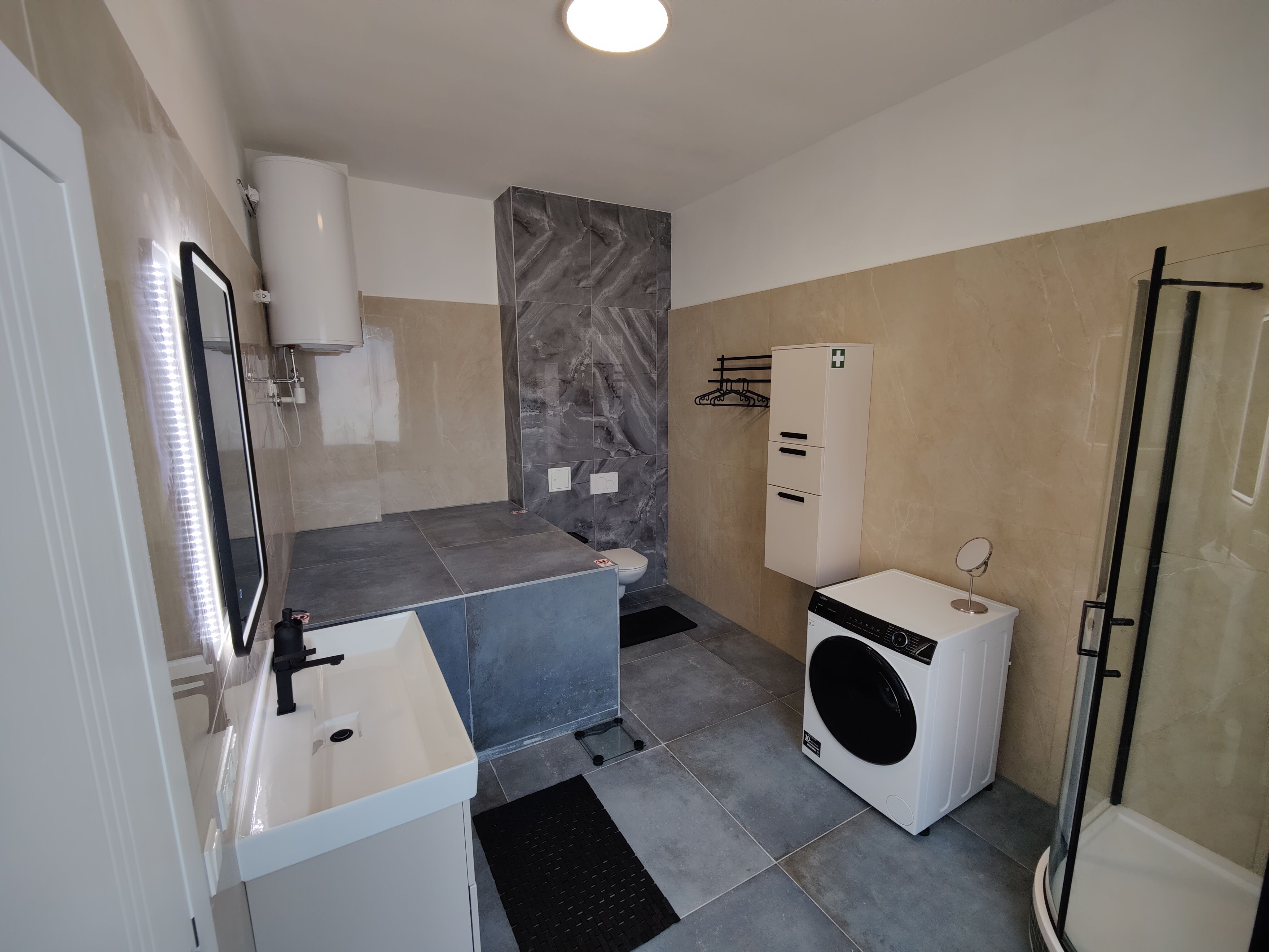Badezimmer mit grauem Fussboden Waschbecken und Waschmaschine 
