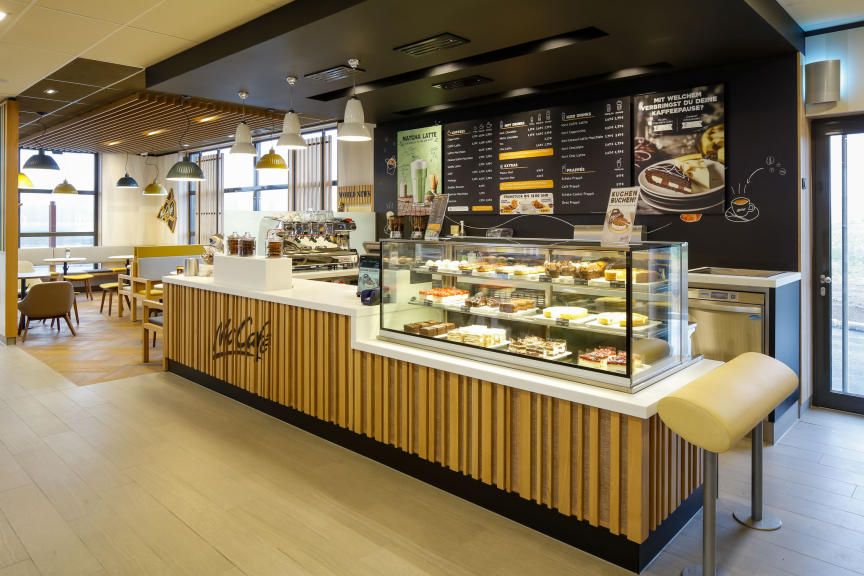 Innenansicht eines McCafé mit Theke und Sitzbereich.
