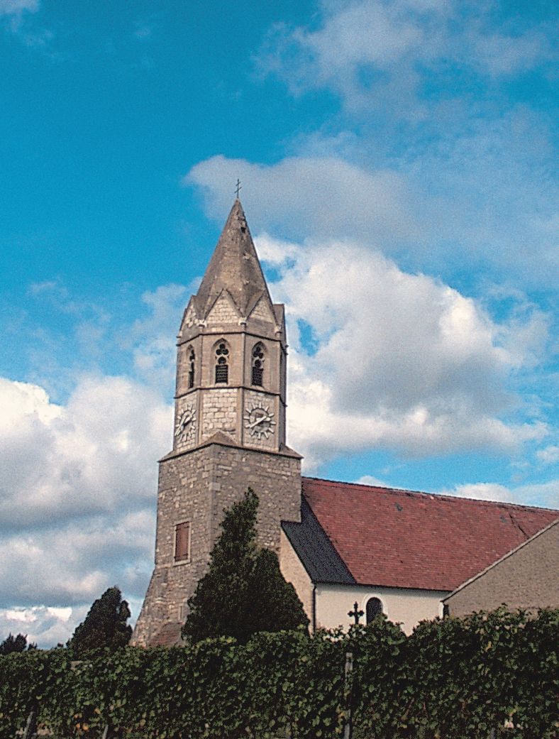 Kirche mit Turm und Uhr vor blauem Himmel.