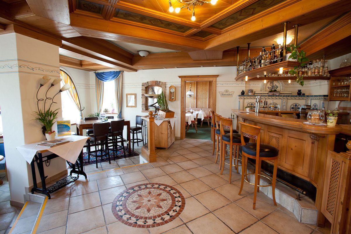 Gemütliche Hotelbar mit Holzmöbeln und dekorativem Fliesenboden.