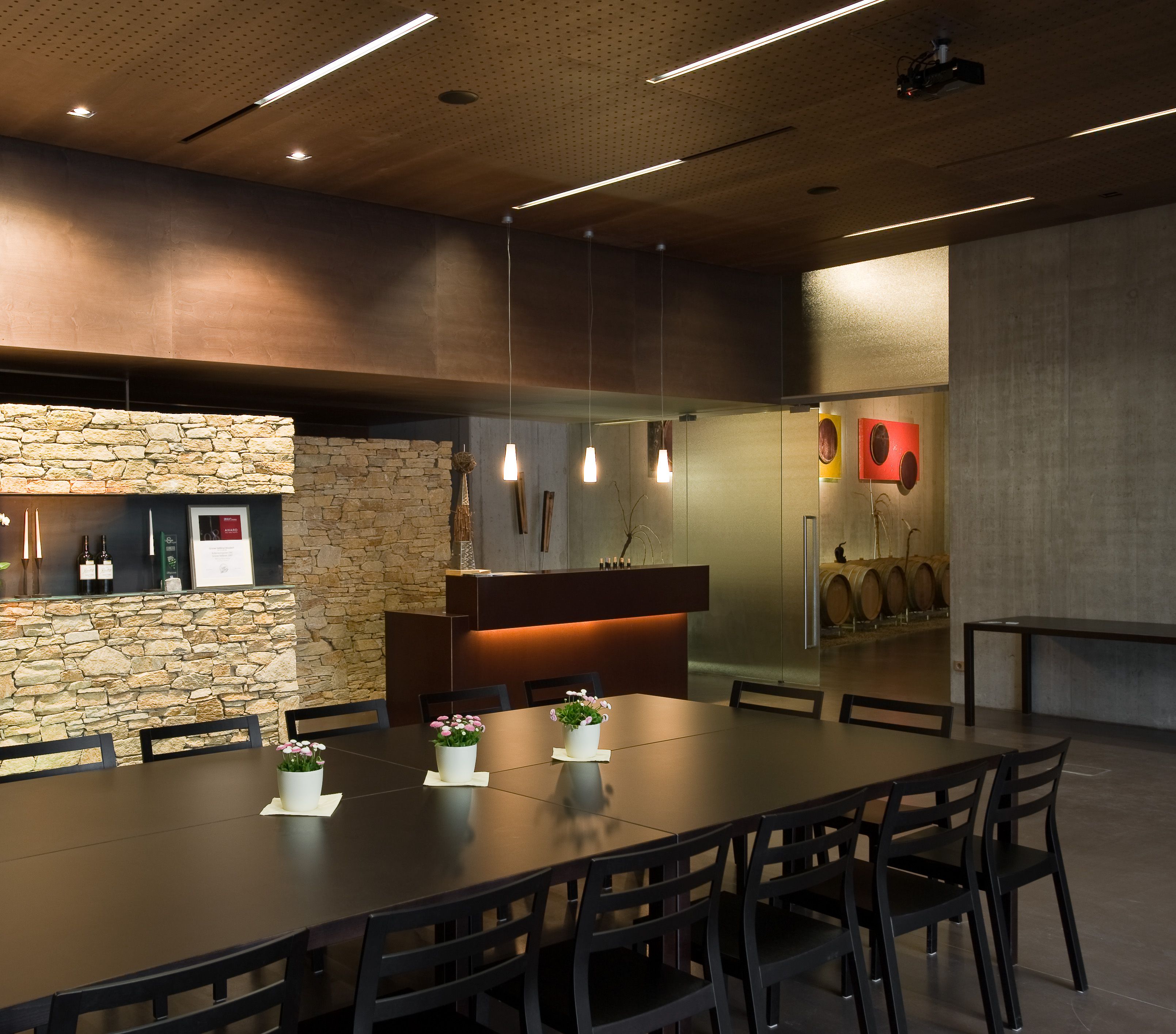 Moderner Verkostungsraum mit Holztisch, Stühlen und Steinwand.