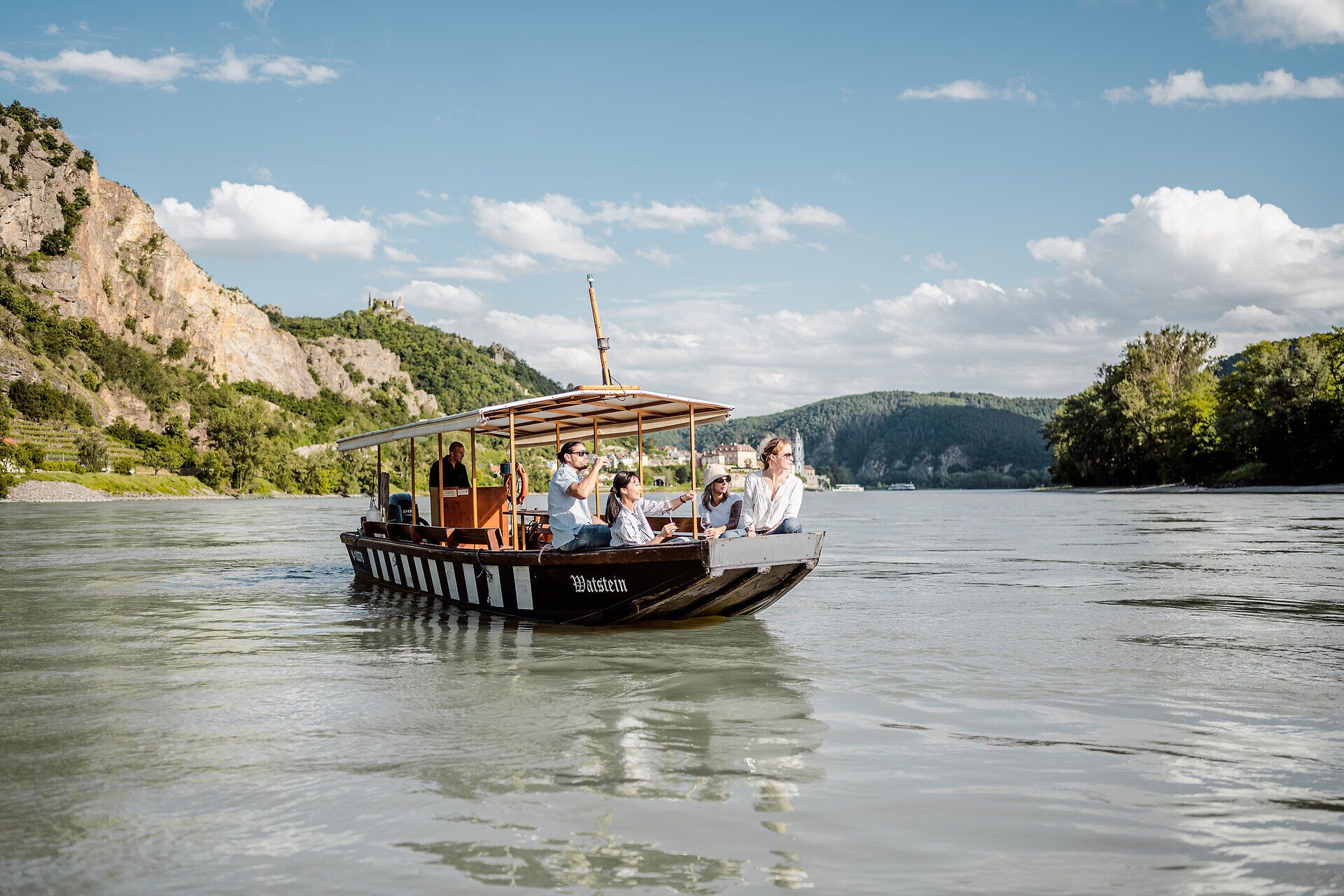 Eine Holzzille mit Menschen fährt auf der Donau in der Wachau.