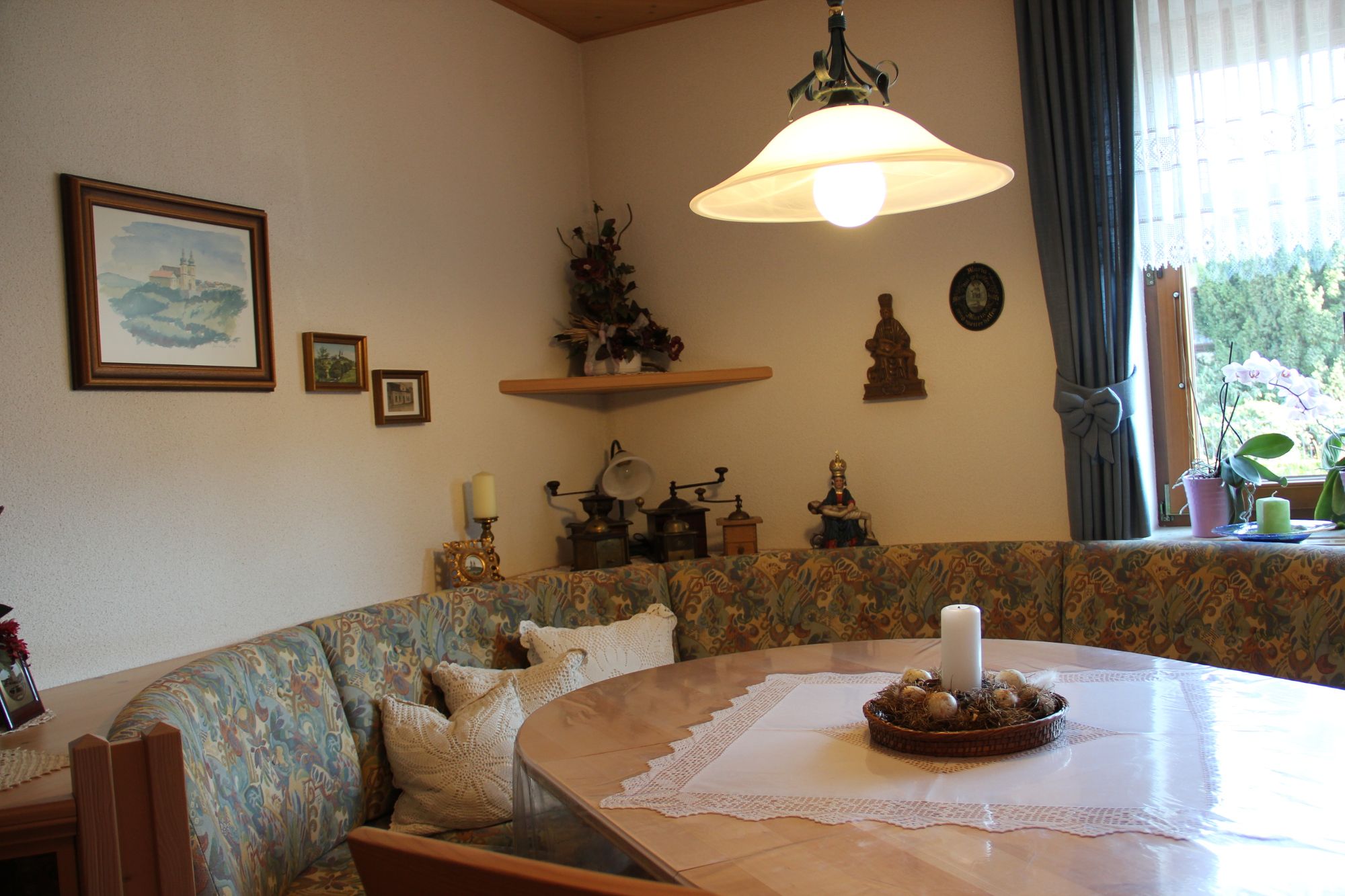 Gemütlicher Frühstücksraum mit Eckbank, Tisch, Kerze und Dekorationen an der Wand.